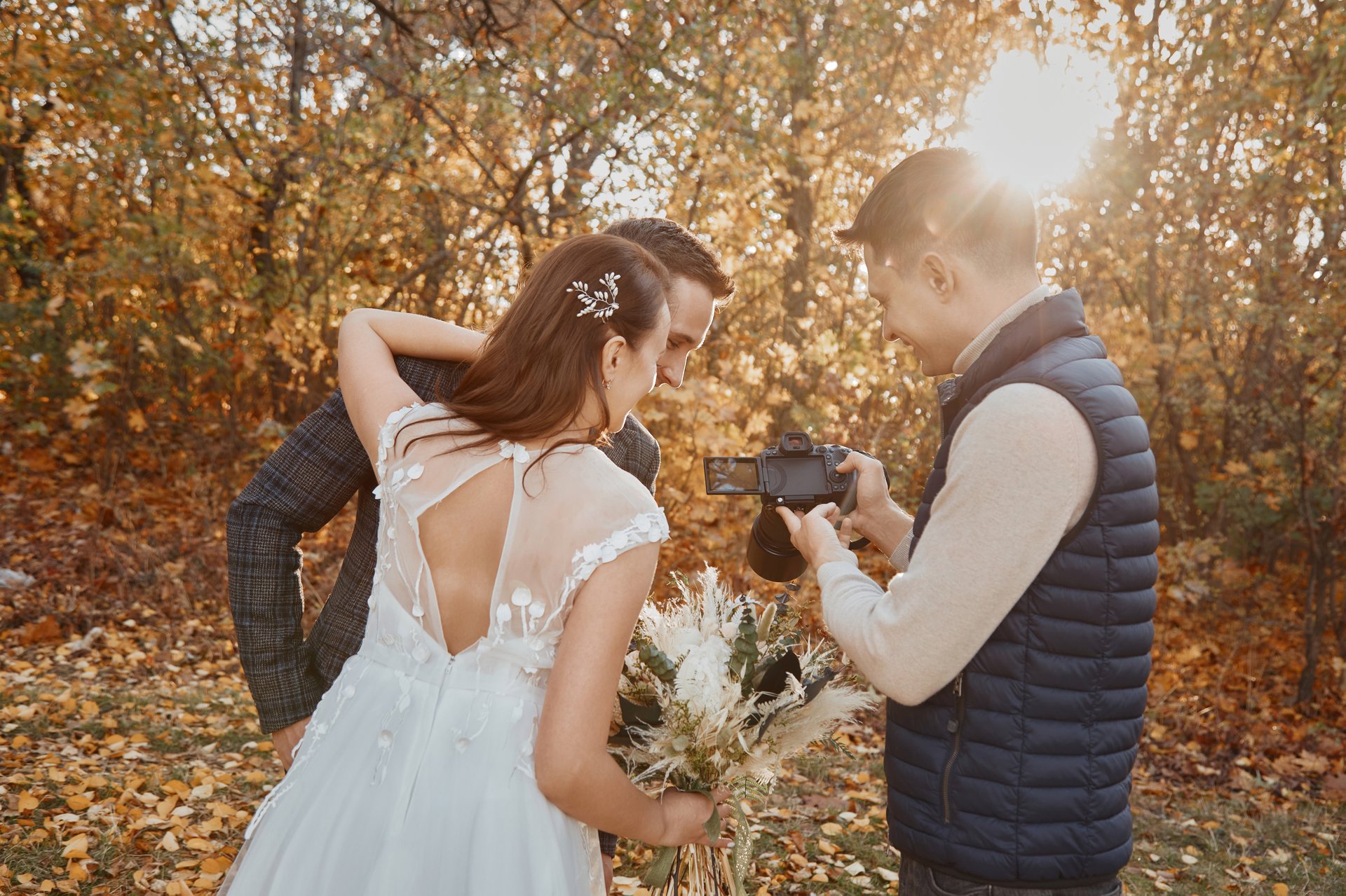 wedding photographer shows just taken photos to wedding couple. bride and groom in nature
