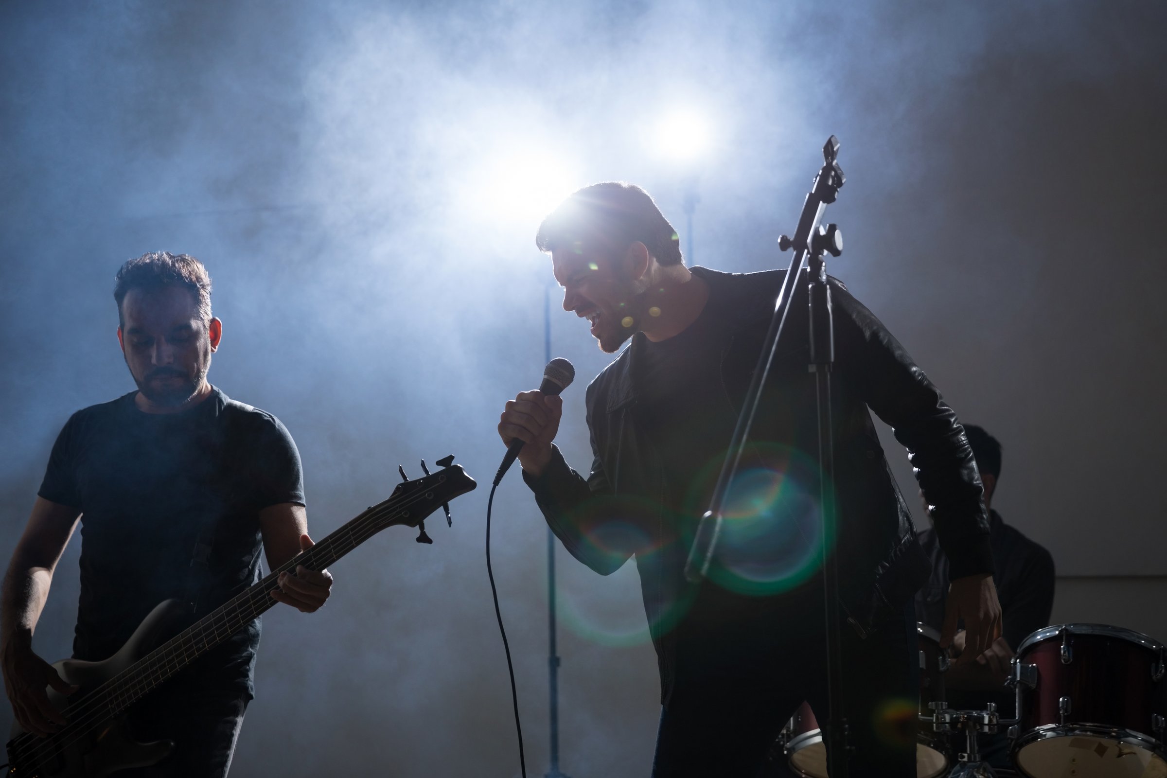 Man singing in microphone with guitarist playing rock music on stage