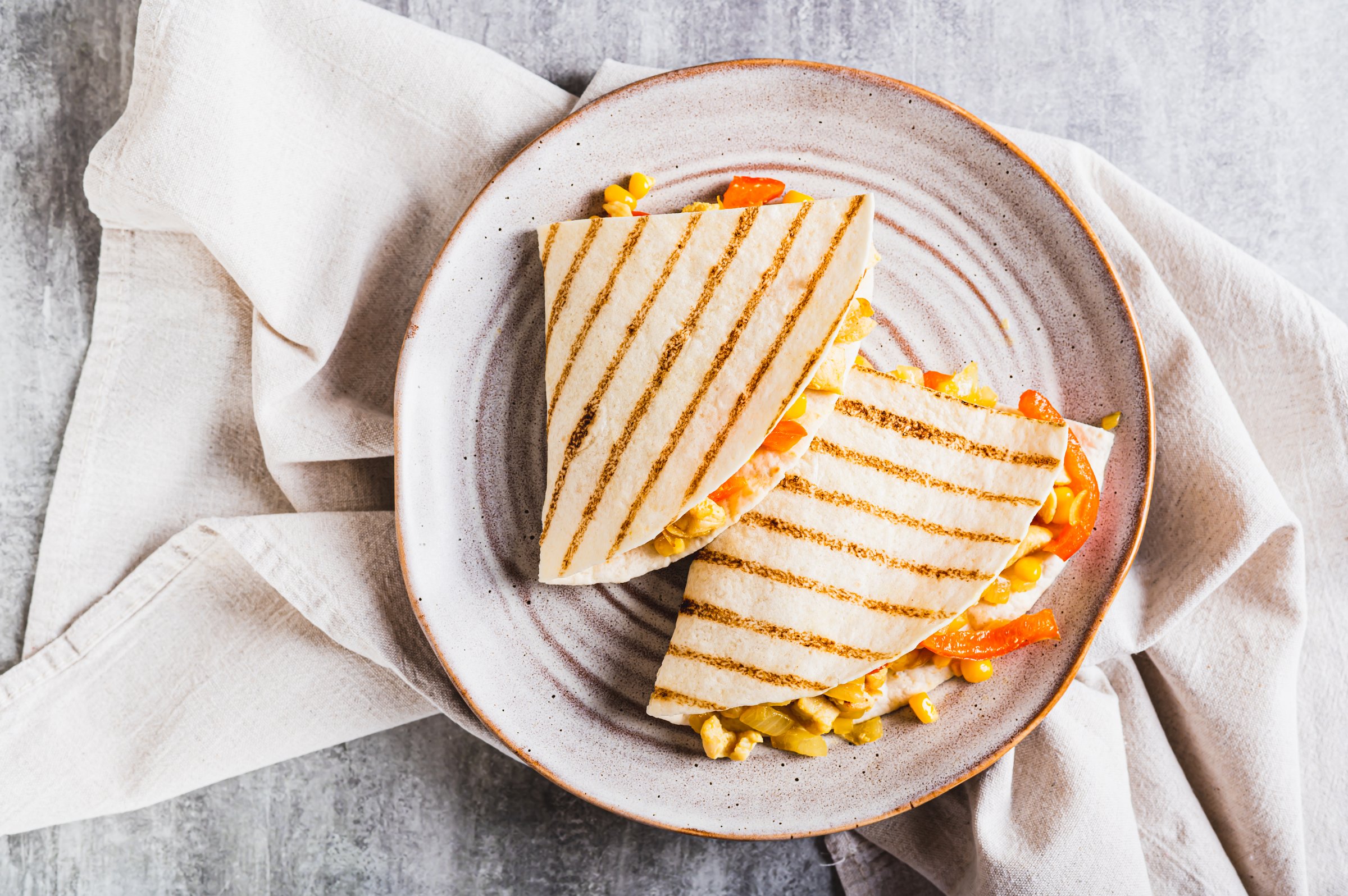 Close up of mexican quesadilla with chicken, corn and bell pepper on a plate on the table top view
