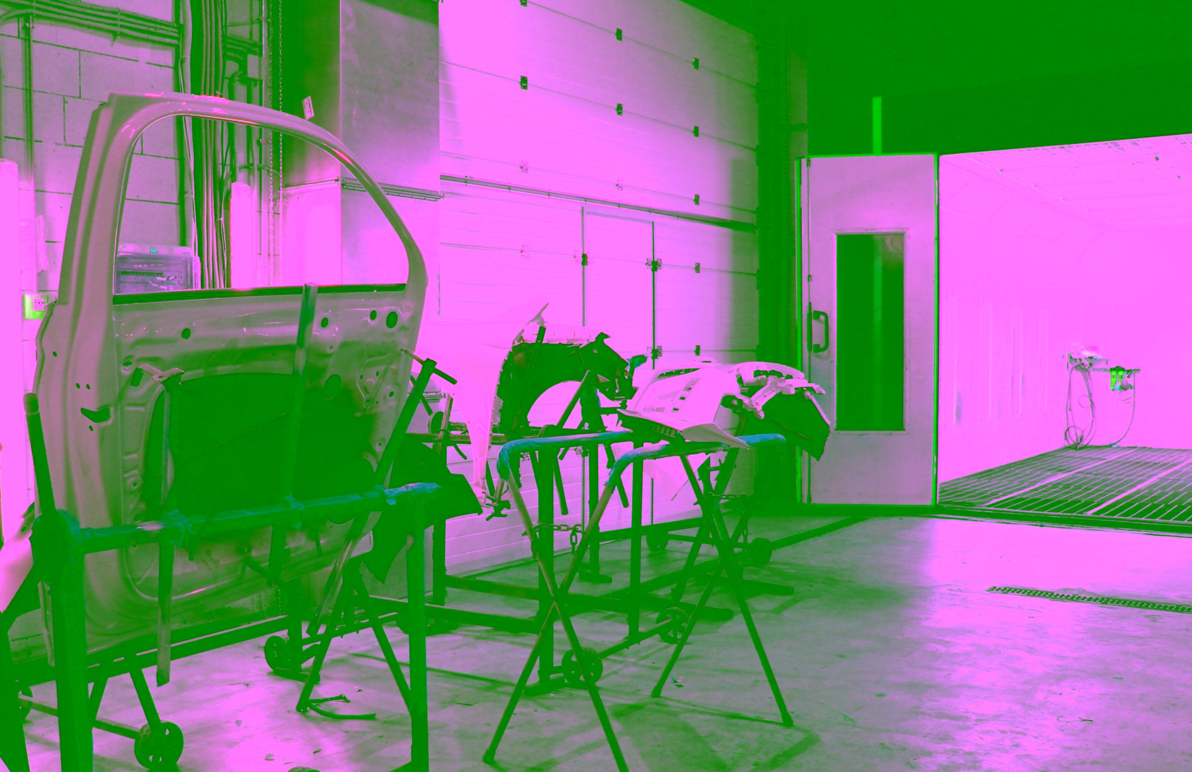 The dismantled car body parts is coated with white paint before a layer of protective varnish is applied