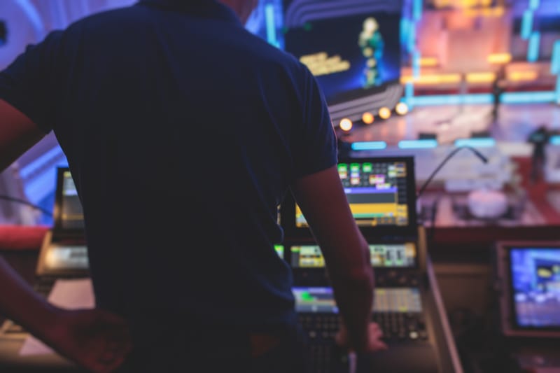 View of a lighting technician operator working on mixing console workplace during live event concert on stage show broadcast, light mixer controller panel, sound technician with professional equipment