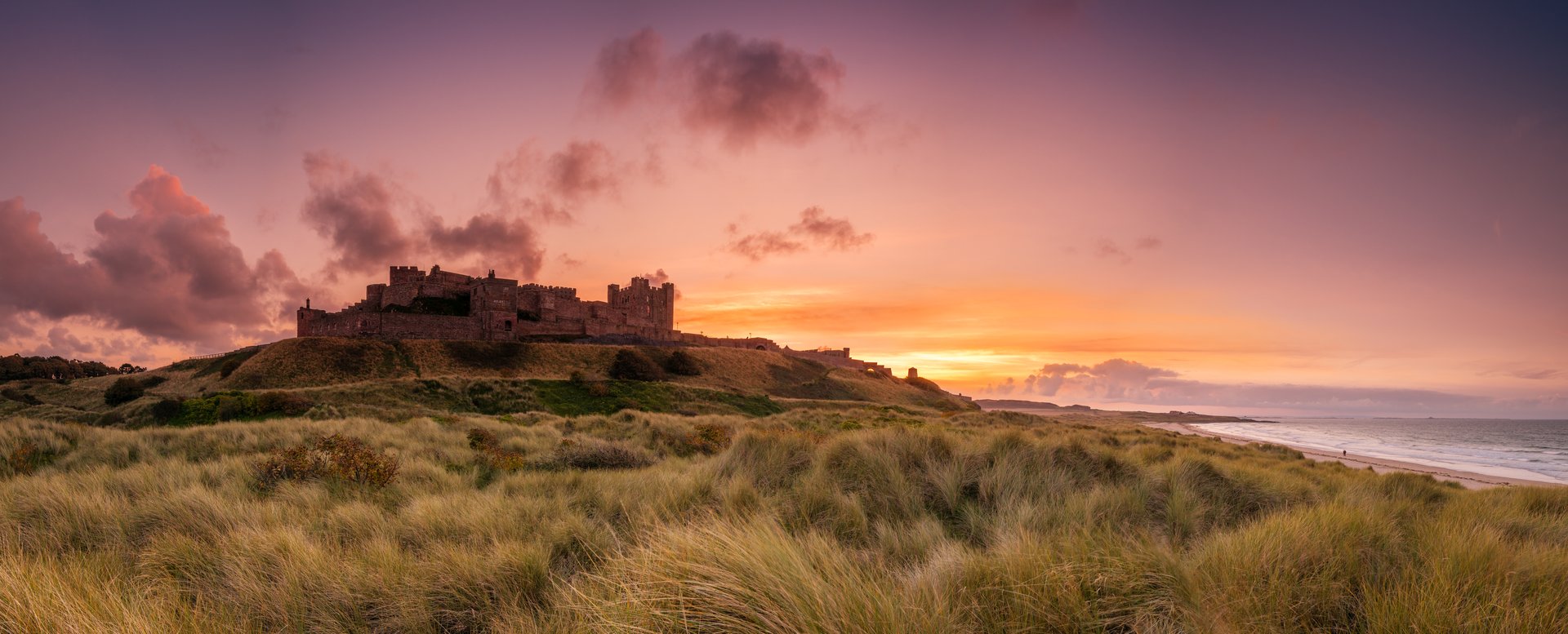 The Iconic Bamburgh Castle on the Northumberland Coastline in panorama at sunset