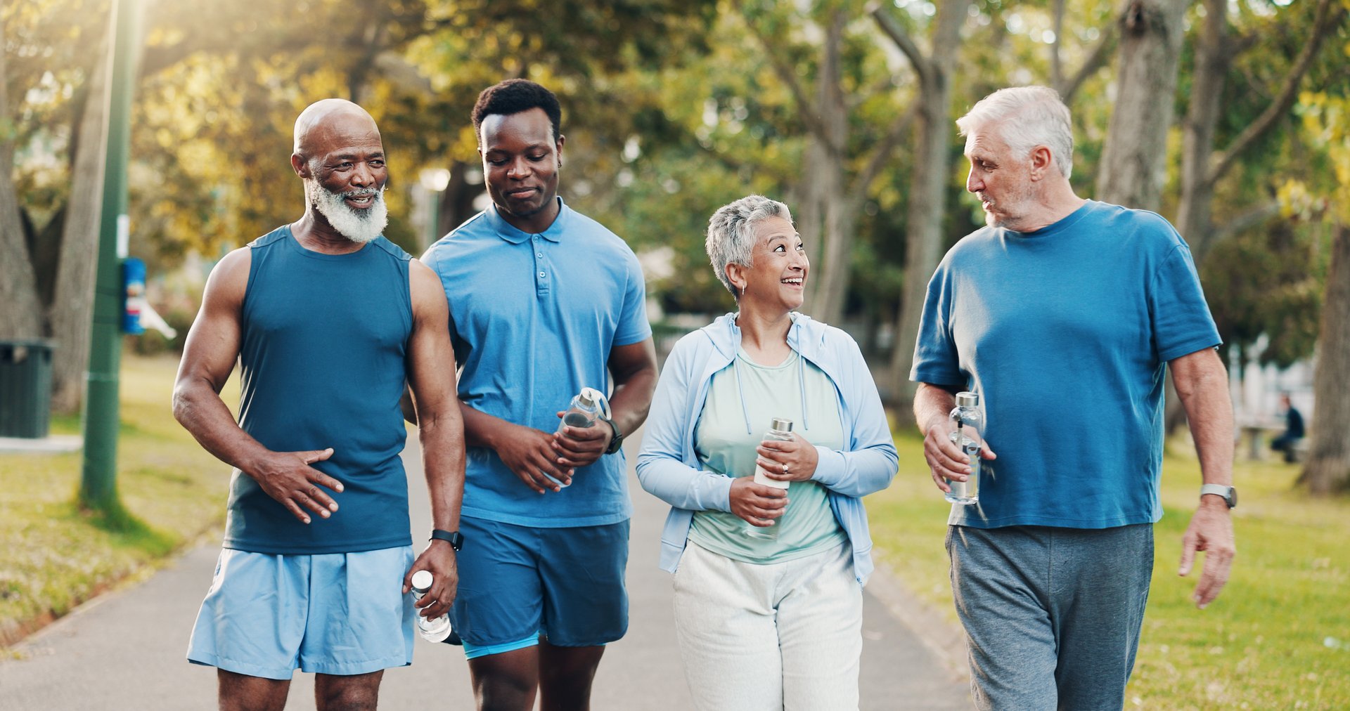 People, talking and walking for fitness outdoor of mobility training, discussion and morning routine. Senior, community and coach with conversation, exercise and motivation for cardio workout at park