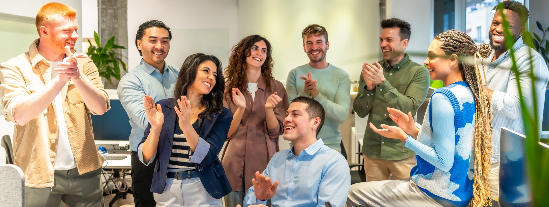 Group of colleagues clapping hands, celebrating a successful project or achievement in a modern office environment