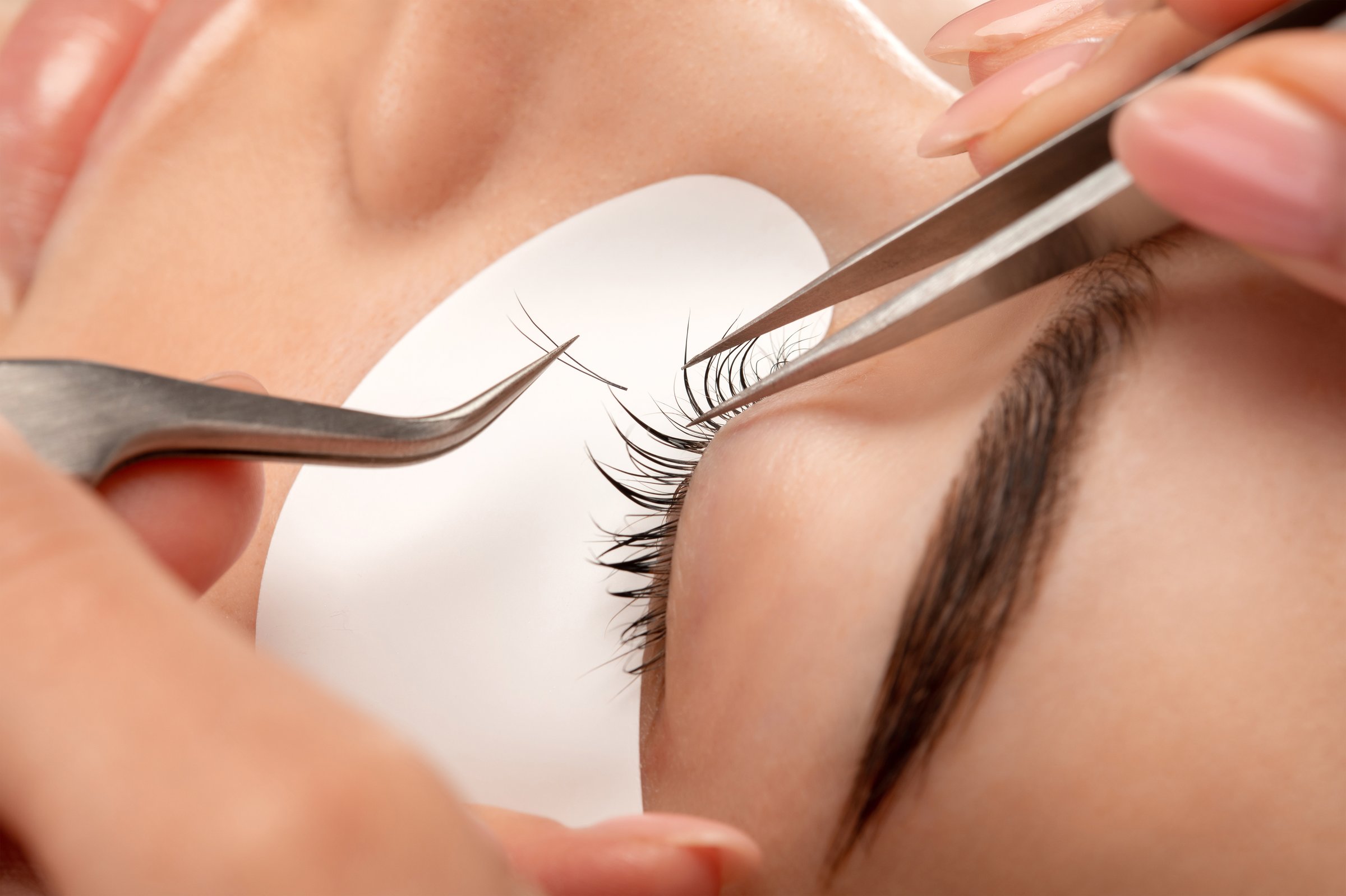 Beautiful Woman with long eyelashes in a beauty salon. Eyelash extension procedure. Lashes close up