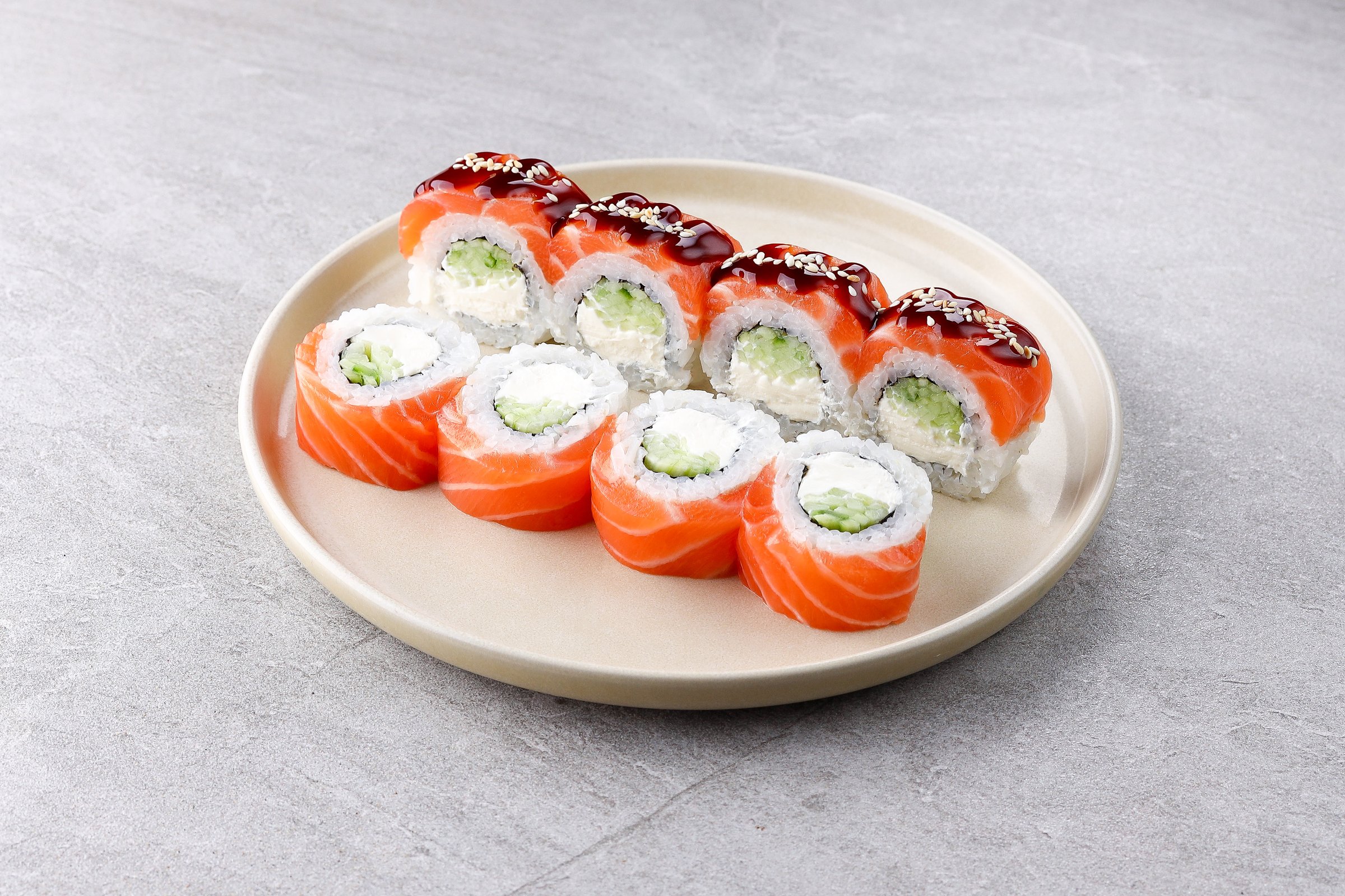 Classic Philly roll wrapped in salmon, filled with cream cheese and cucumber, with sesame teriyaki glaze on top.