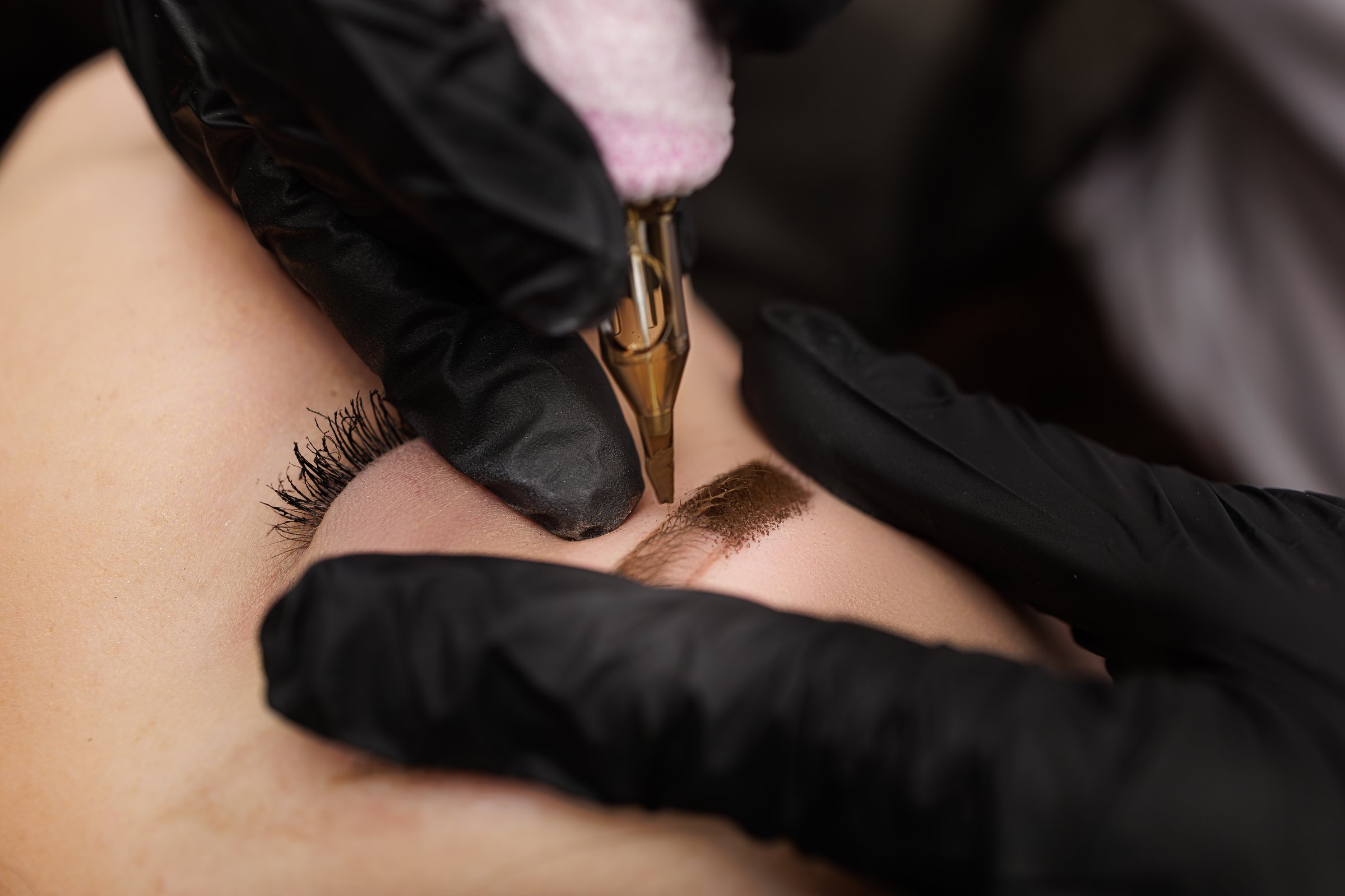 Macro photo introduction of pigment into the skin with a tattoo machine eyebrow correction. Second PMU procedure in a month of permanent eyebrow makeup. Permanent makeup correction.