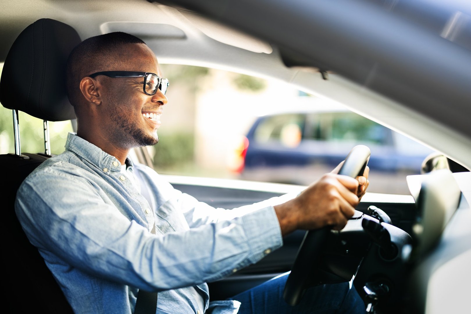 Successful African American CEO happily driving new corporate car in summer, symbolizing achievement and success in business world.