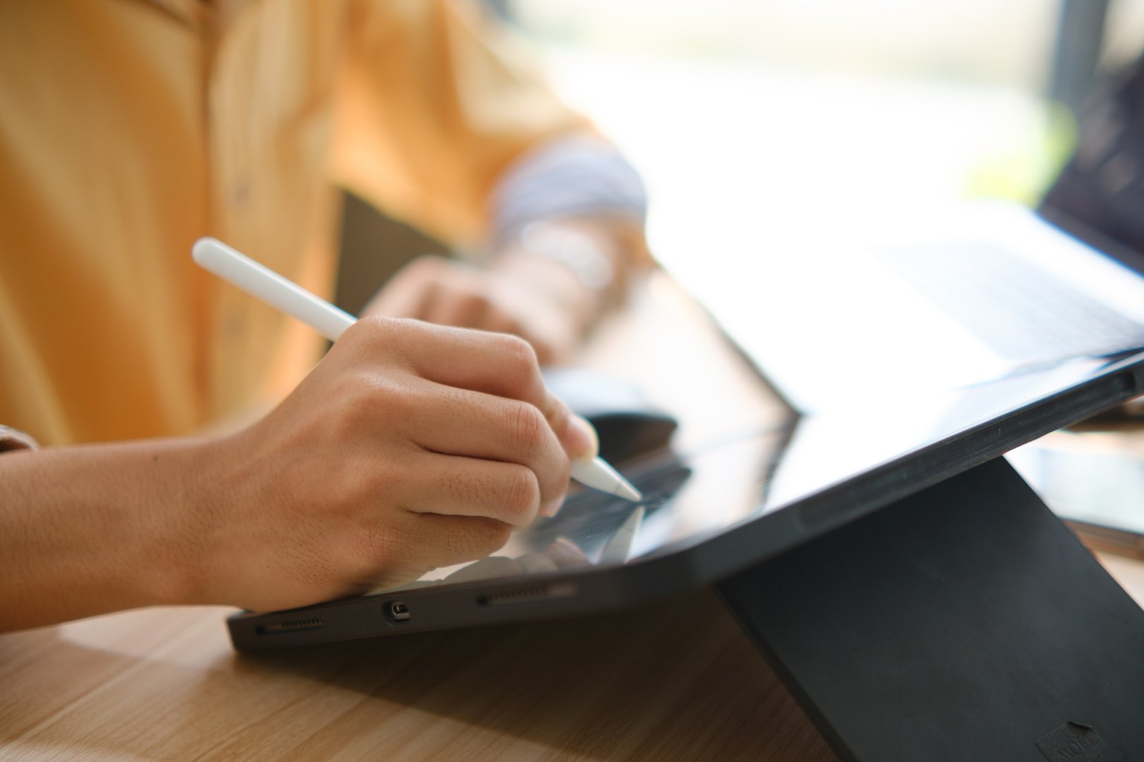 Male web designer drawing with graphic tablet at table in office, closeup