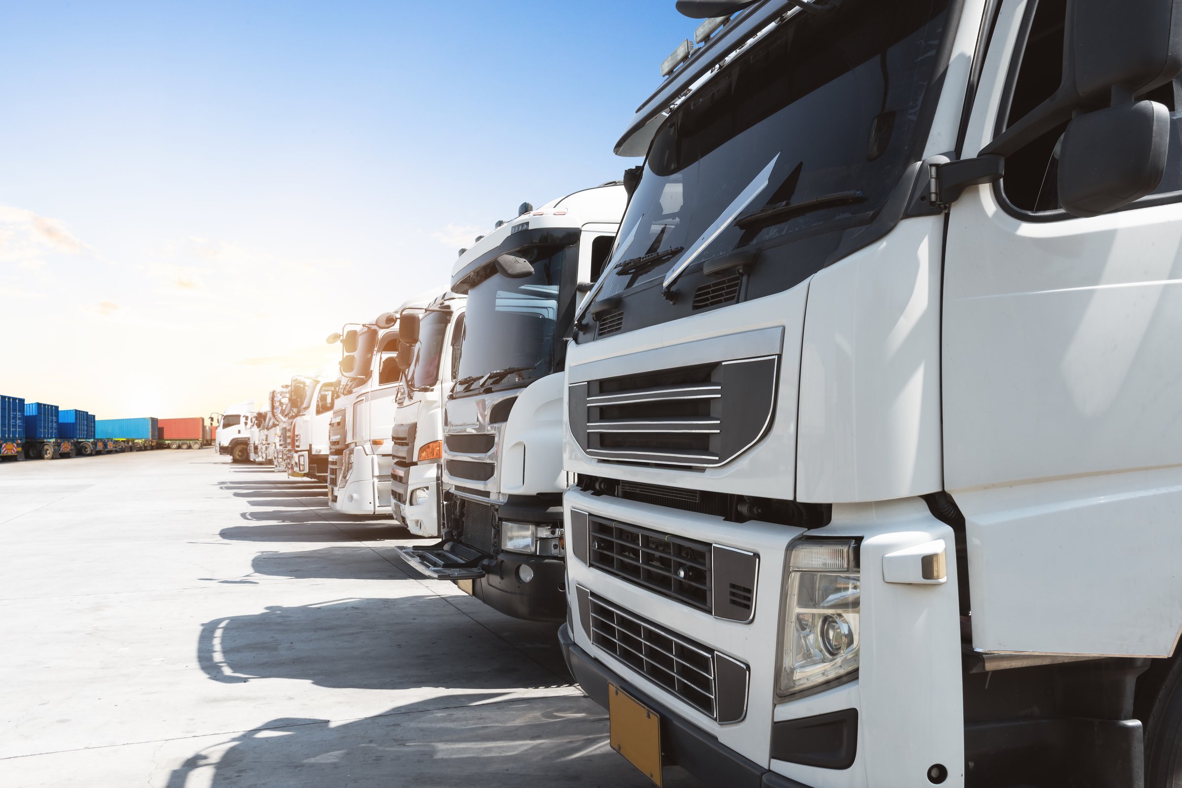 Row of Semi Trucks Parked on The Parking Lot. Big Rig, Tractor Truck. Shipping Cargo Container Trucks at The Port. Economy Business Transport on Road. Trucking. Freight Logistics Truck Transportation.