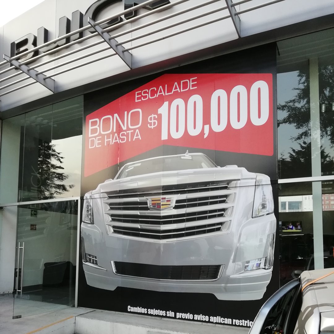 Car dealership ad for Cadillac Escalade offers a bonus of up to $100,000. Large image of the vehicle displayed.