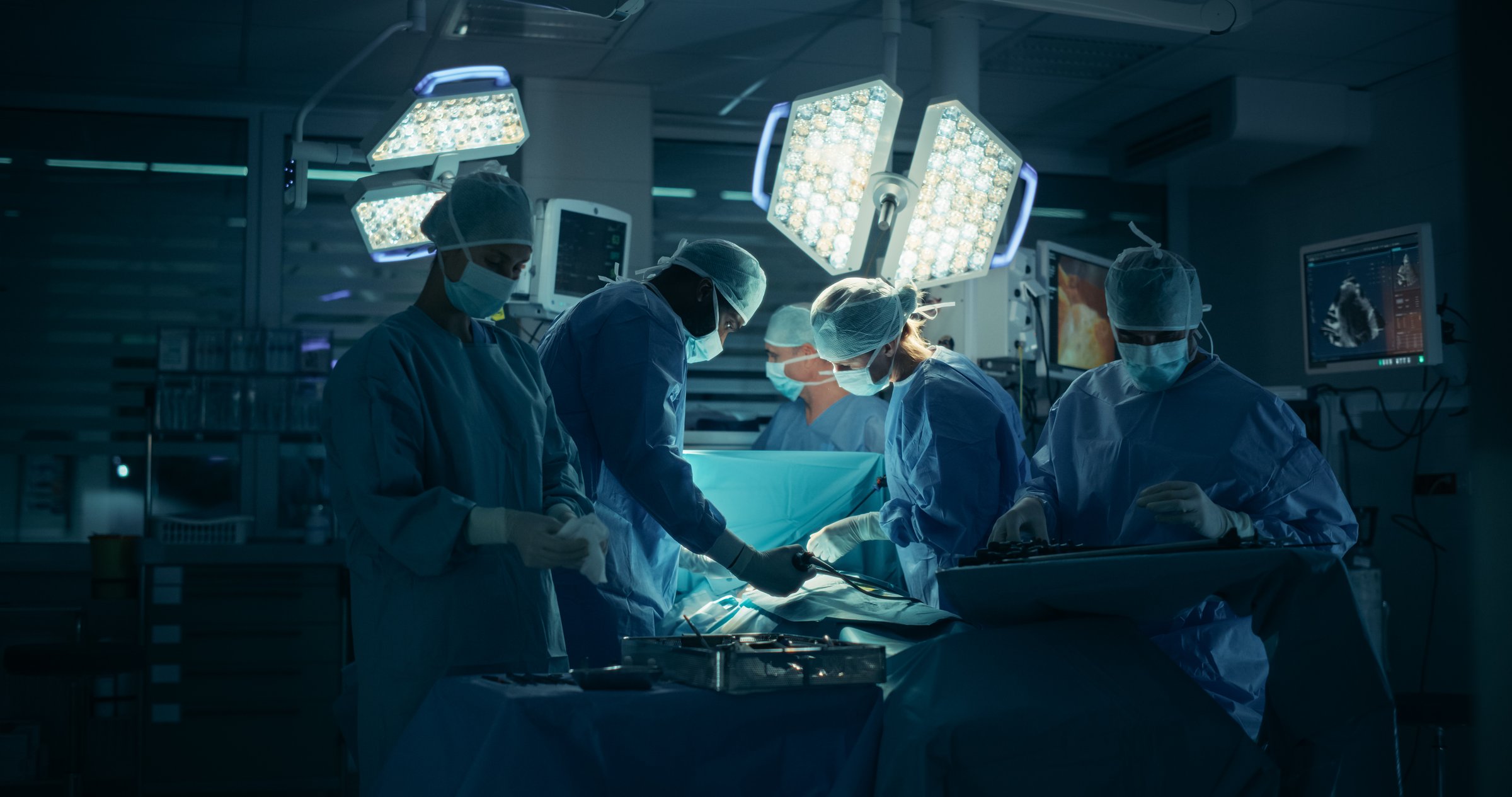 Dressed in Full Protective Gear, Diverse Surgeons and Nurses Coordinate as a Team Around the Operating Table, Saving Life of a Patient with Their Combined Skills and Medical Training