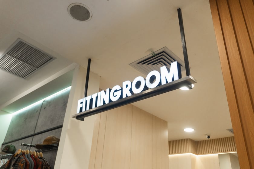 Fitting room sign on the wall above the door opening in clothing store.