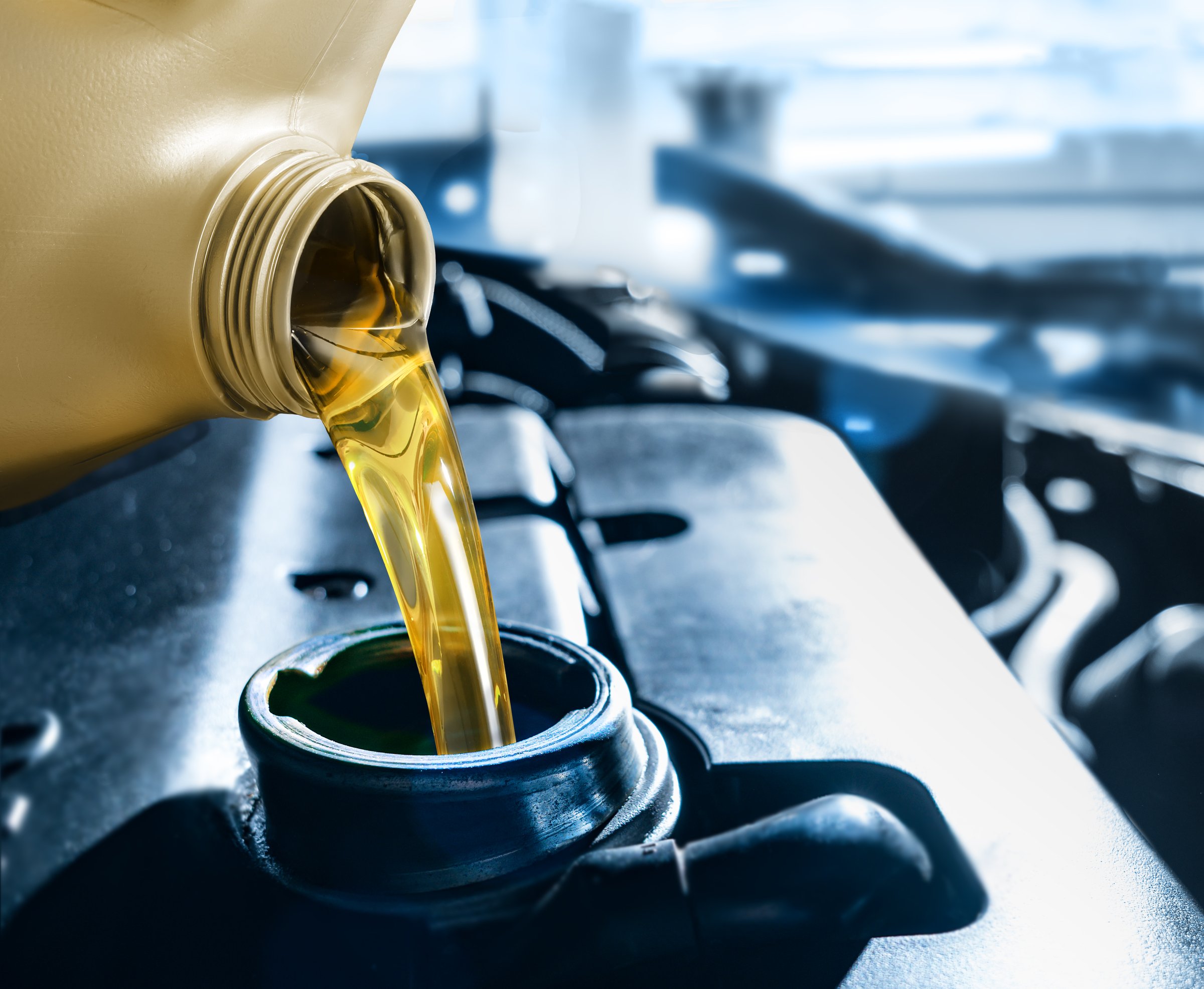 Pouring motor oil from plastic canister in car repair service center. Regular and routine vehicle maintenance utilizing engine oil is essential for achieving optimal performance levels