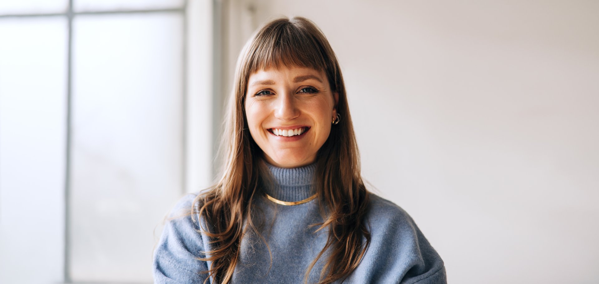 Portrait of a happy young businesswoman smiling at the camera while standing in an office. Cheerful female entrepreneur working in a creative workplace.