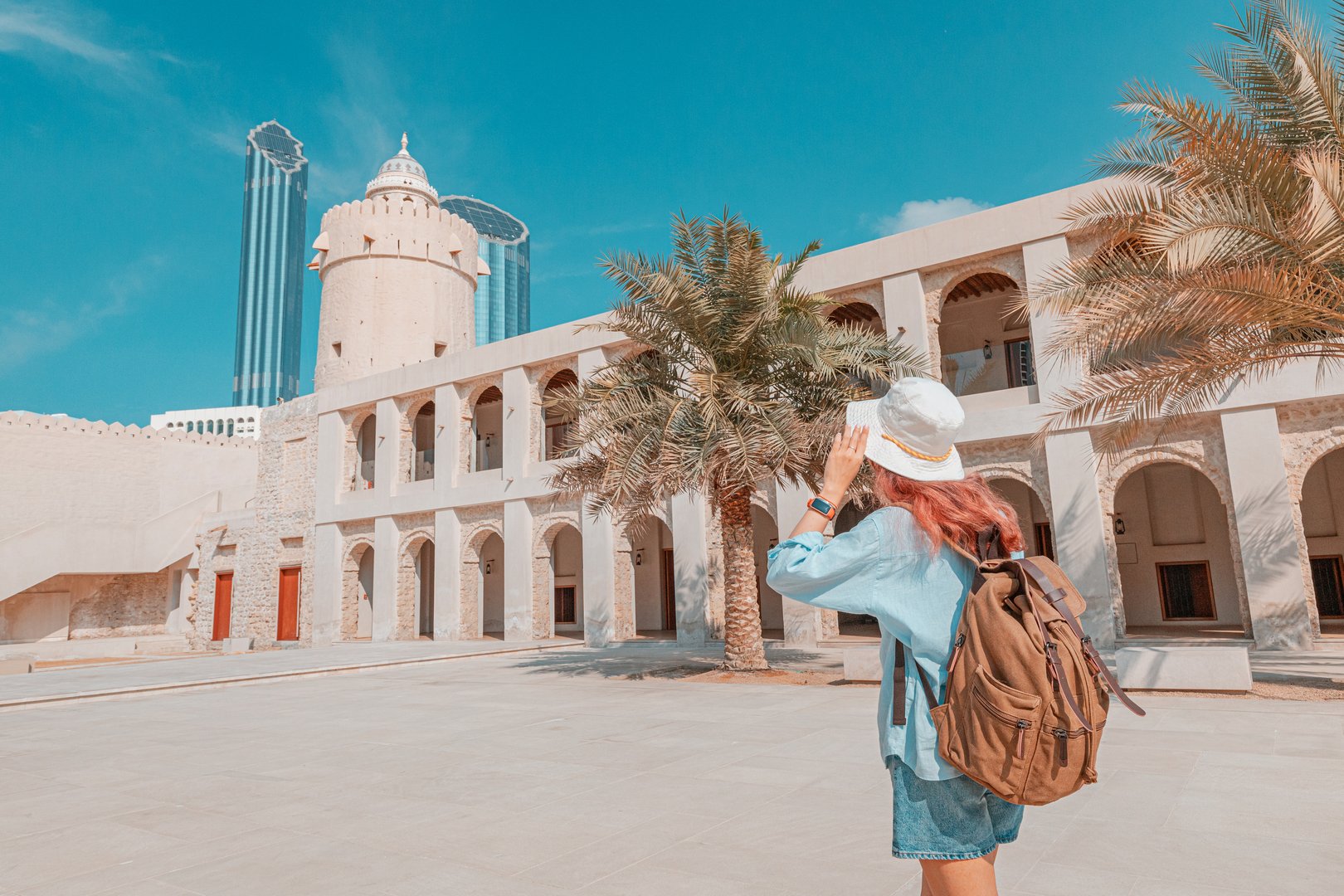 Woman walking through traditional architecture with modern skyscrapers in the background in Abu Dhabi, UAE
