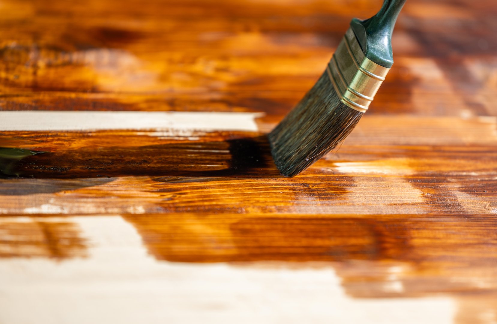 Worker painting house exterior with brown wood protective color.Closeup