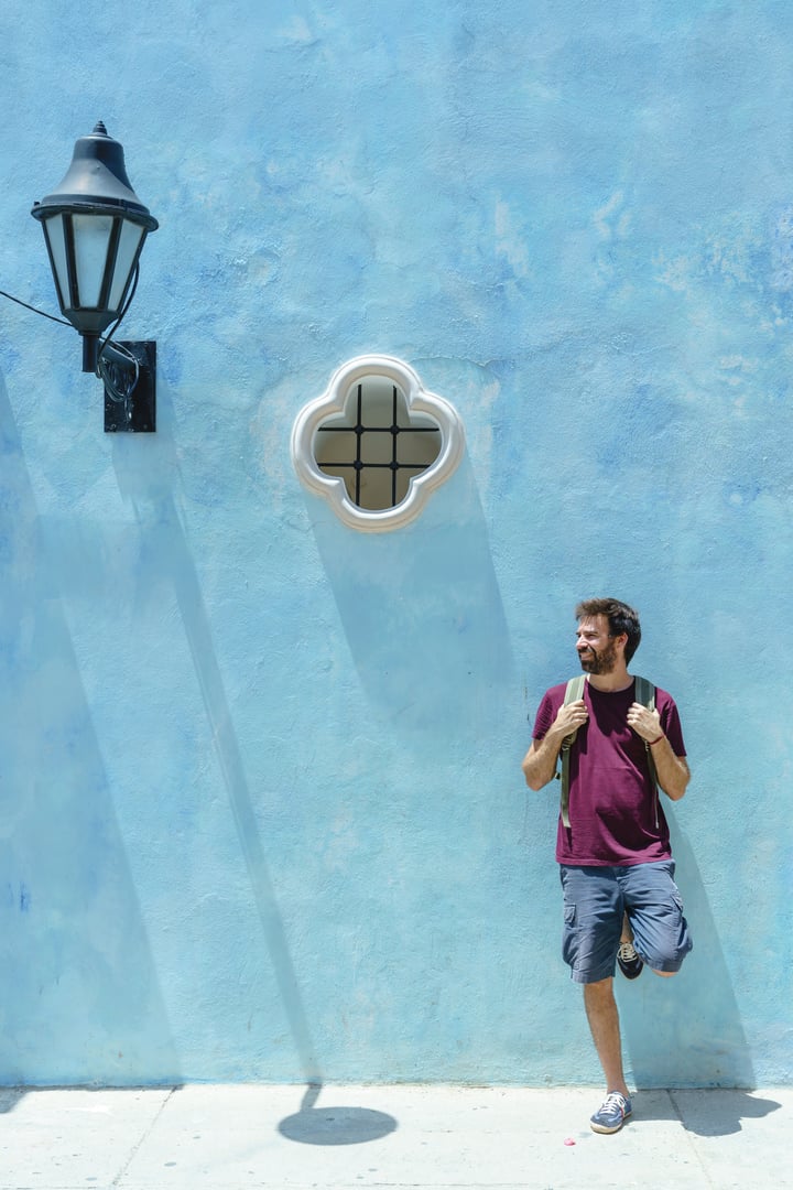 Vertical view of latin man sightseeing isolated on blue background. Travel to Colombia concept.