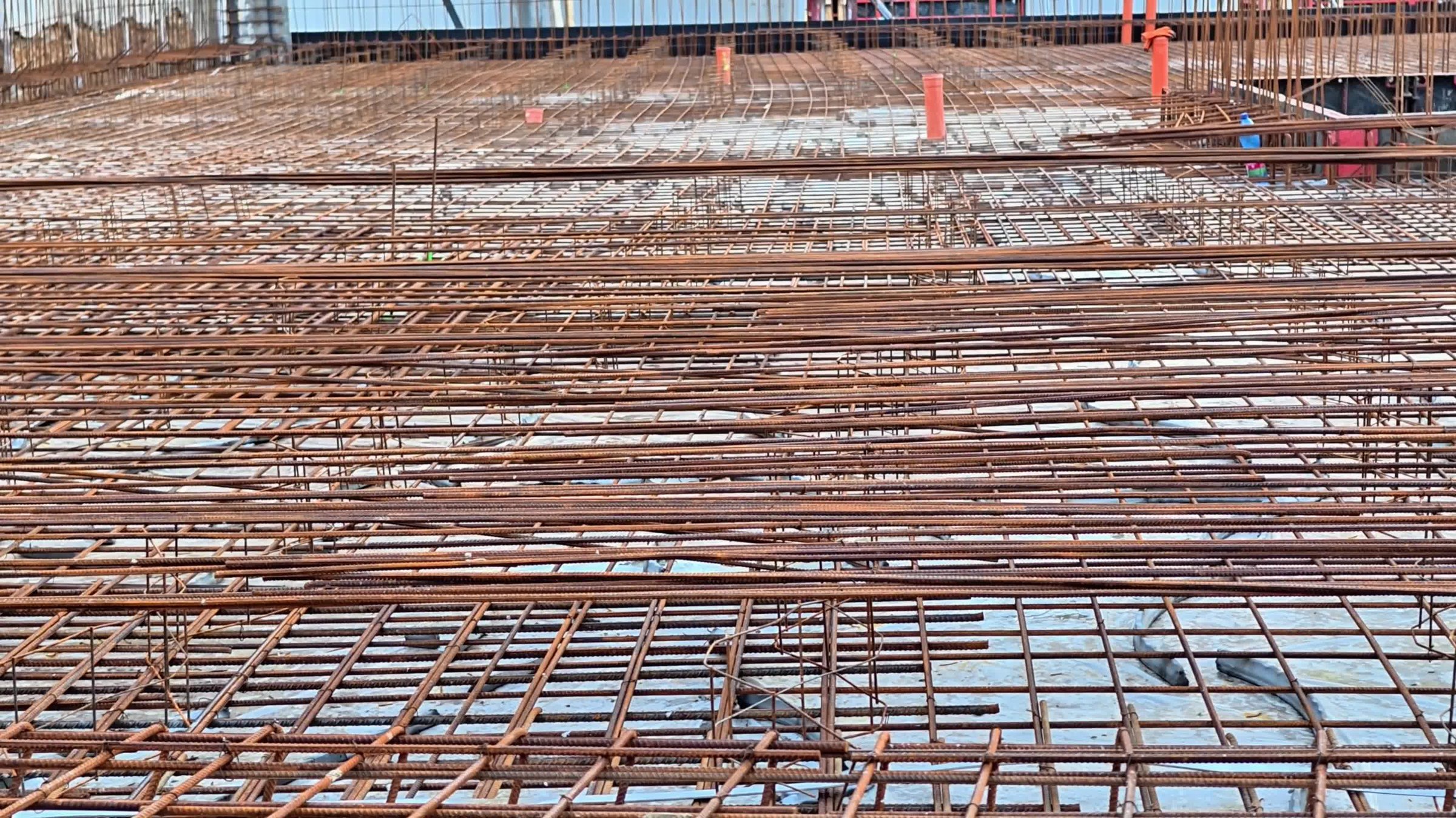 A closeup image of an active construction site shows a steel framework ready for the upcoming concrete pouring