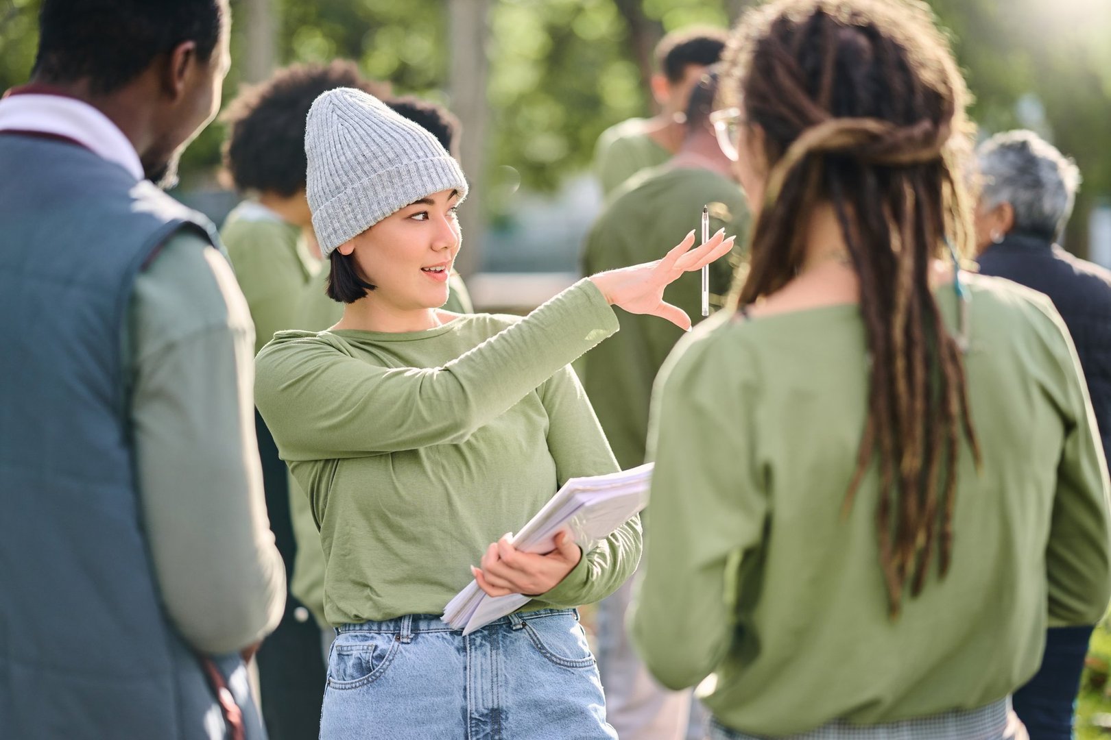 Volunteer schedule, community cleaning leader and charity work outdoor with Asian woman talking. Recycle team, collaboration and eco friendly job with manager giving recycling teamwork orders