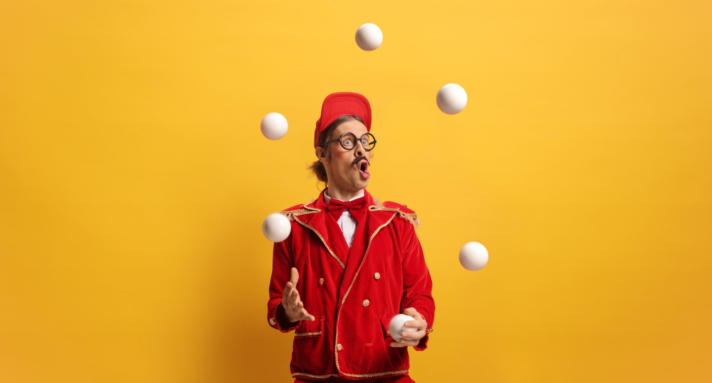 Entertainer in a red suit juggling with balls