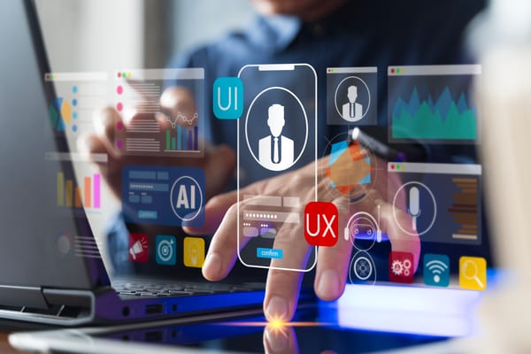 Close up of businessman hand working on laptop with UI and UX icons, artificial intelligence, data analytics, and digital interface technology for mobile application and software development concept.