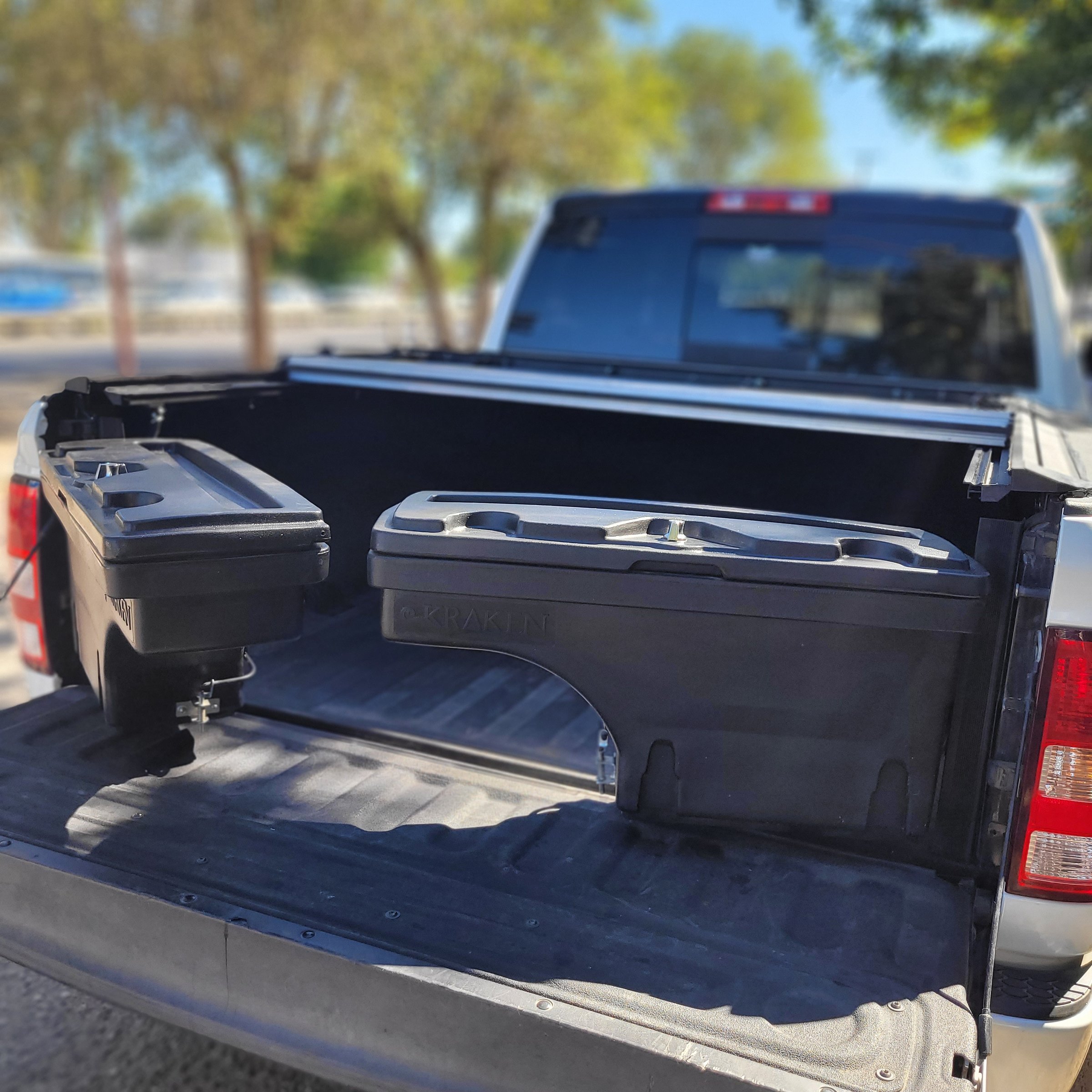 Pickup truck bed with storage boxes positioned near the tailgate on a sunny day.