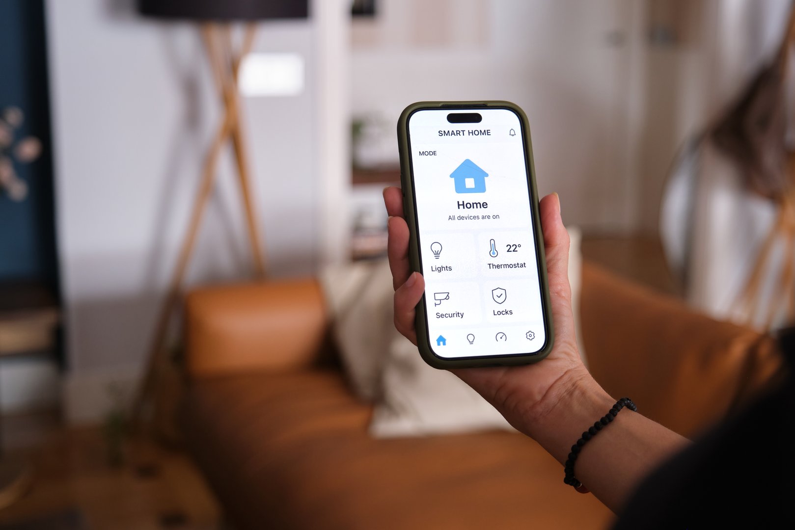Woman using smartphone app to control smart home devices, including lights, thermostat, security, and locks