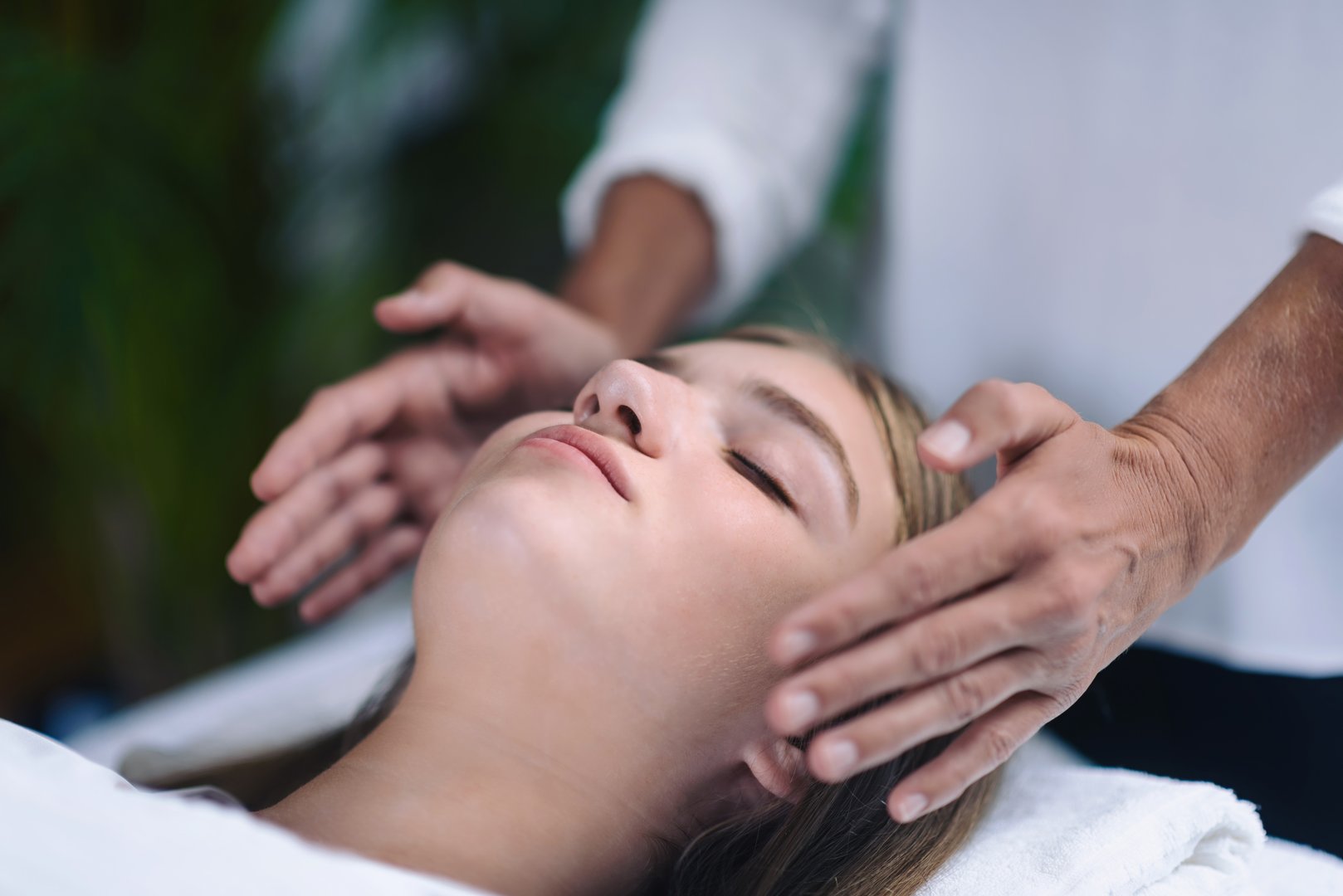 Midsection Of Therapist Giving Reiki Treatment To Teenage Girl On Face At Spa