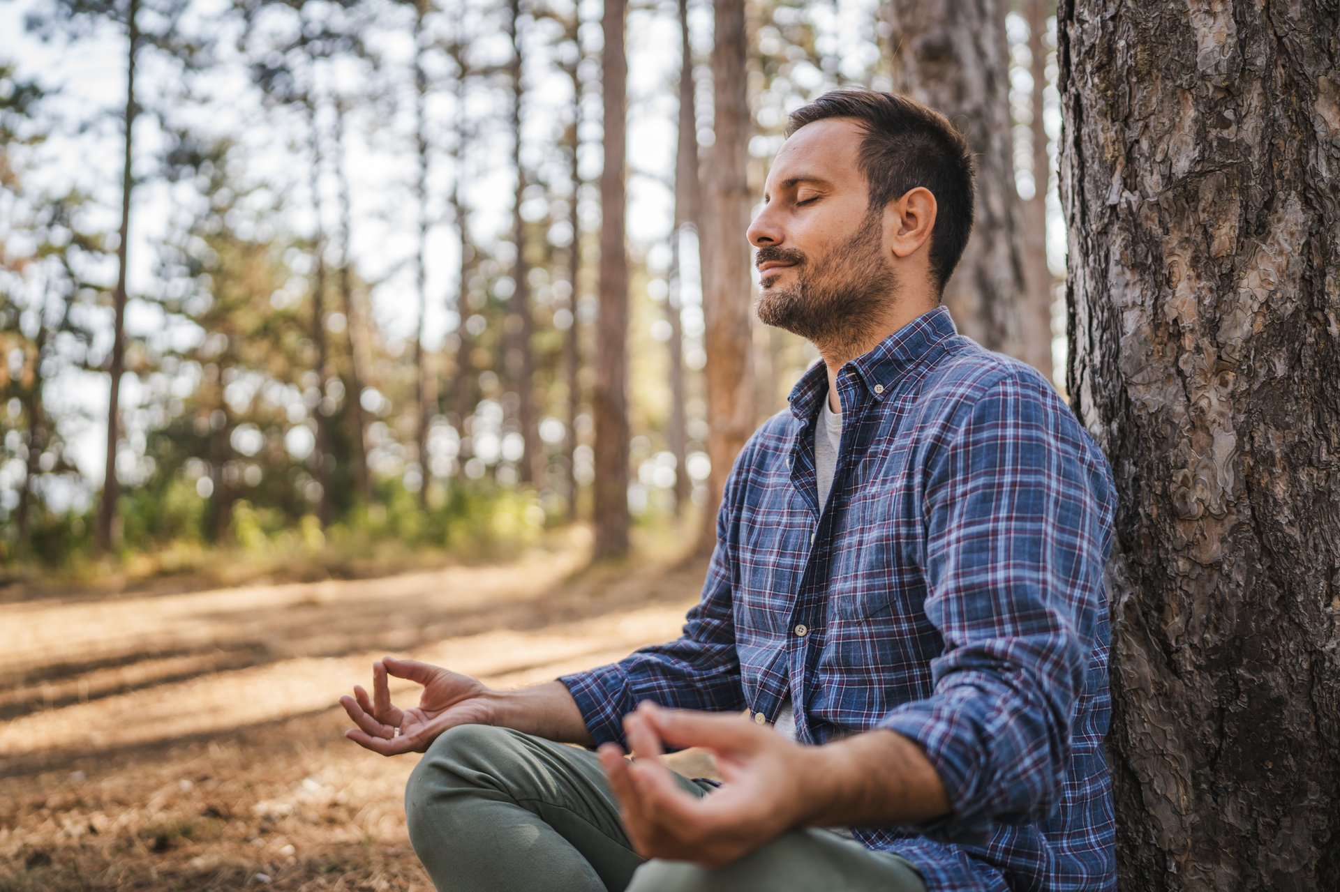 Adult man camper practice meditation and breath exercise in front tree
