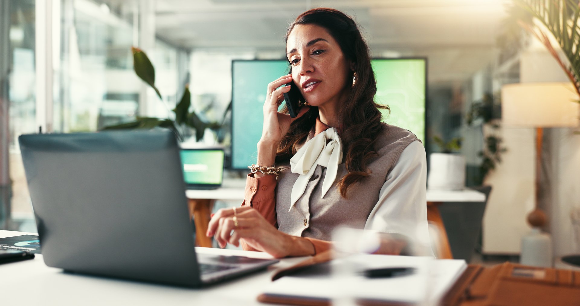 Phone call, creative and woman in office, negotiation and conversation with contact for budget and talking. Discussion, event planner and planning for booking of venue with laptop, online and person