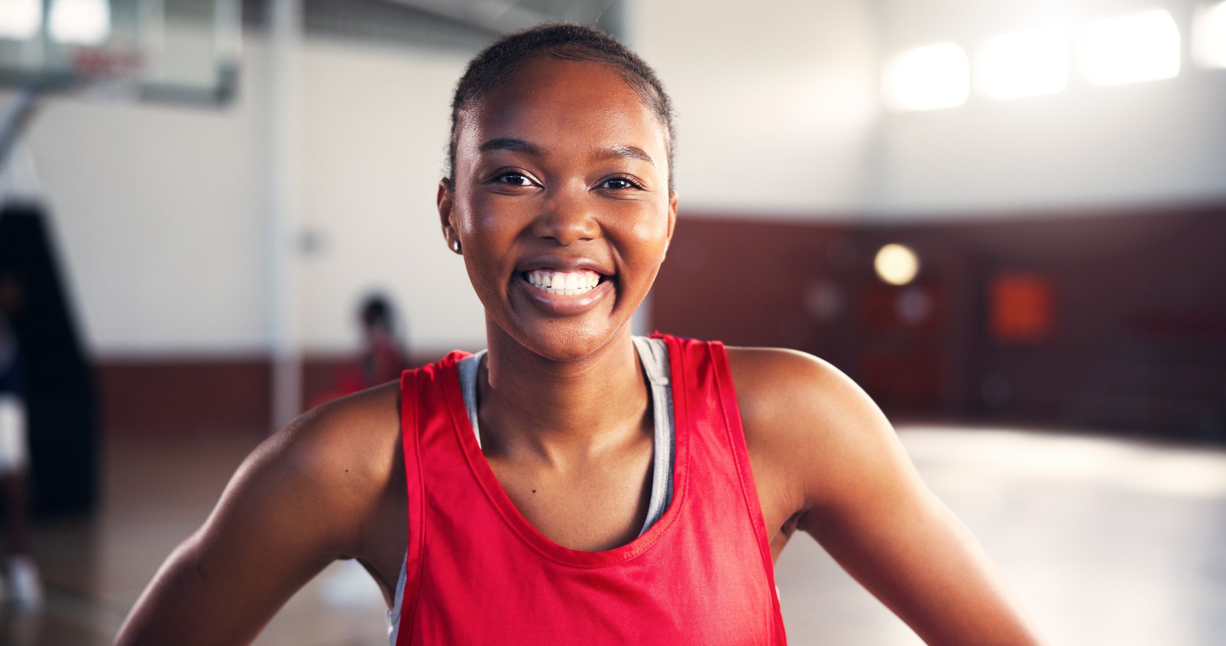 Portrait, smile and black woman at basketball court for sports, workout or practice for training. Player, happy athlete and female person in gym for fitness, competition and wellness with confidence