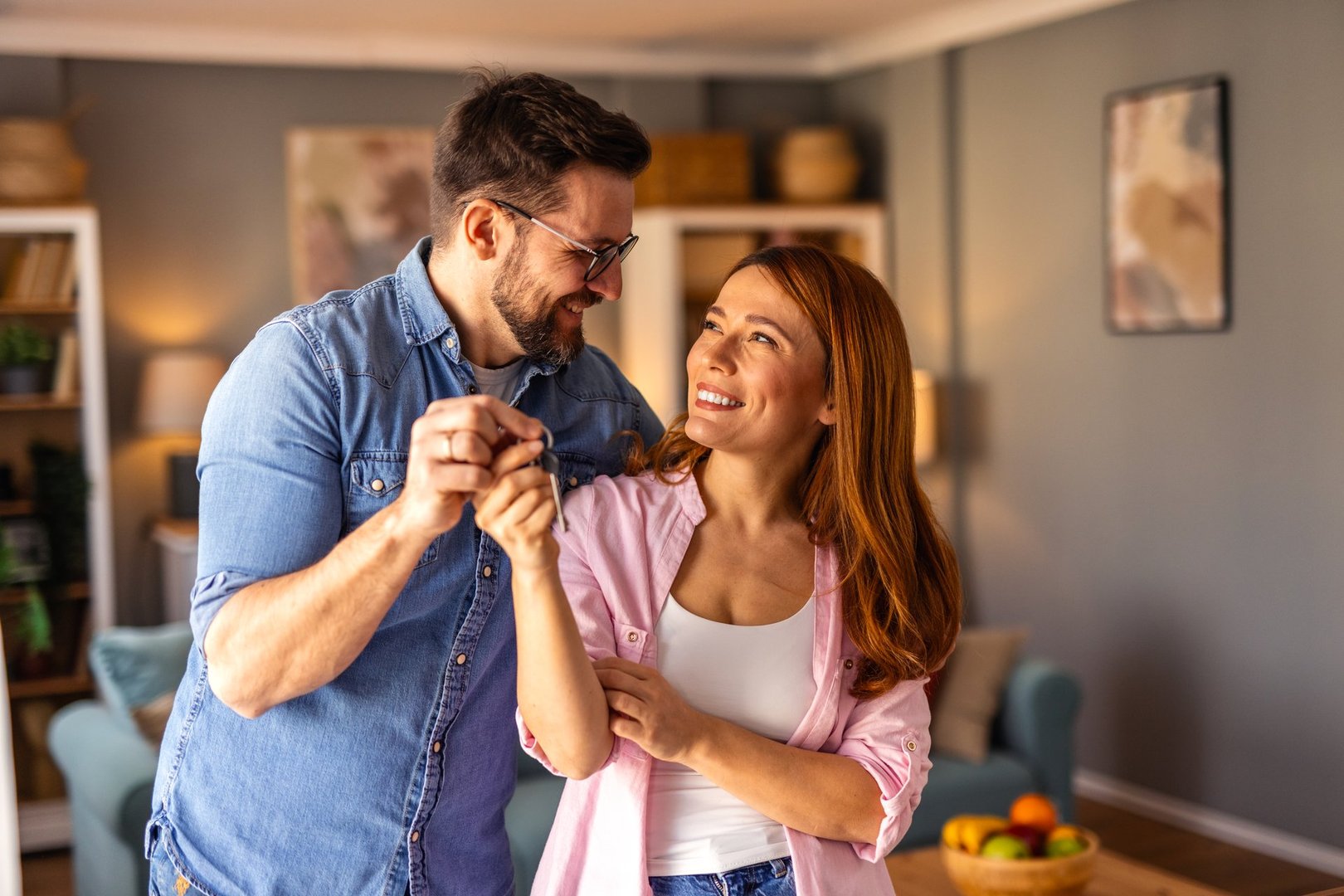 A couple is standing together, happily showing the key to their new home. The image captures excitement, achievement, and a fresh start as they celebrate homeownership in a joyful moment.