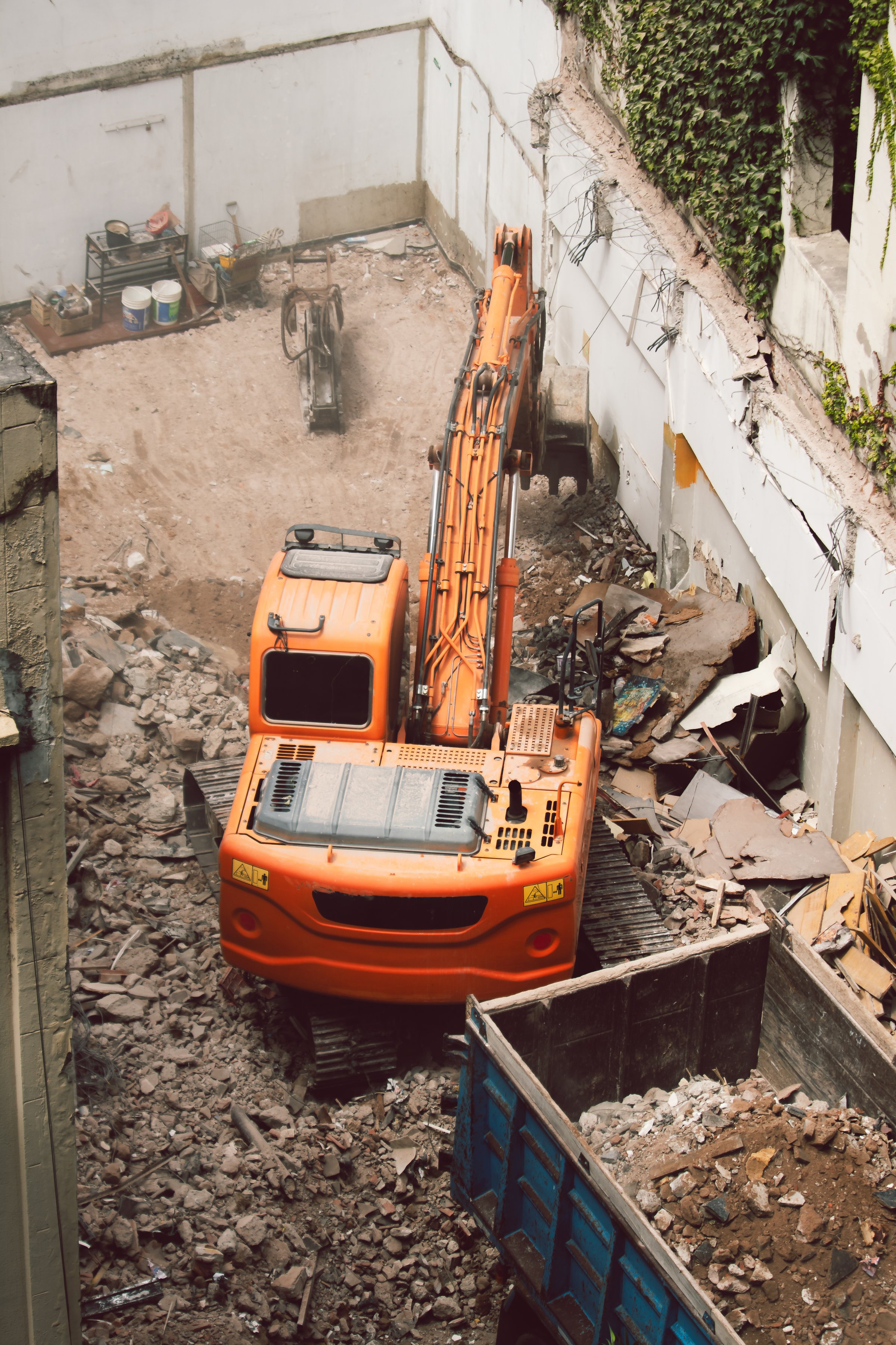 Excavator removing debris from a demolition site and dumping it into the back of a truck