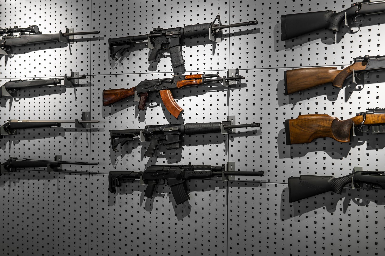Collection of rifles and carbines. Various firearms hang on special mounts on the wall. Weapon background.