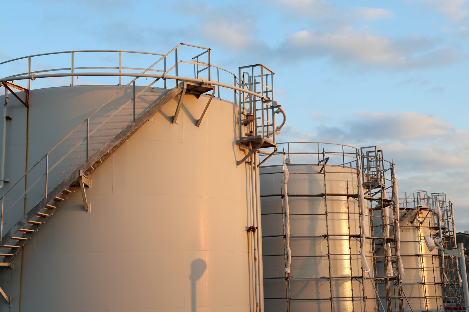 fuel tanks in industrial area, shining in late afternoon sun, under a blue sky