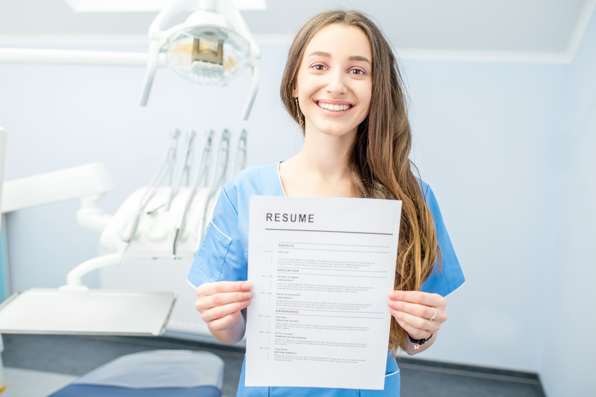 Young dentist assistant or student holding resume for a job at the dental office