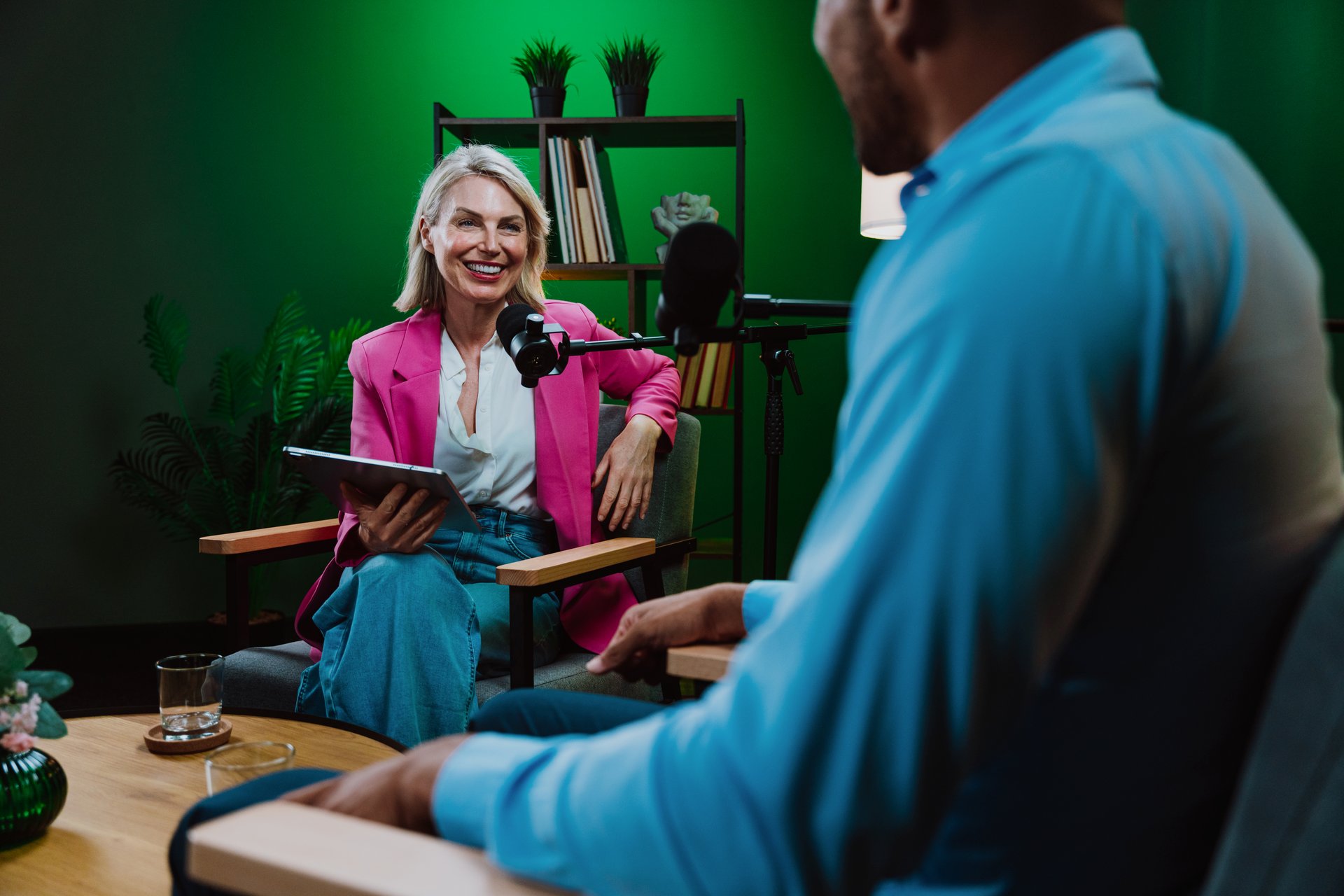 Group of three individuals engaging in a dynamic conversation during a recording session in a professional podcast studio, broadcasting with microphones and camera