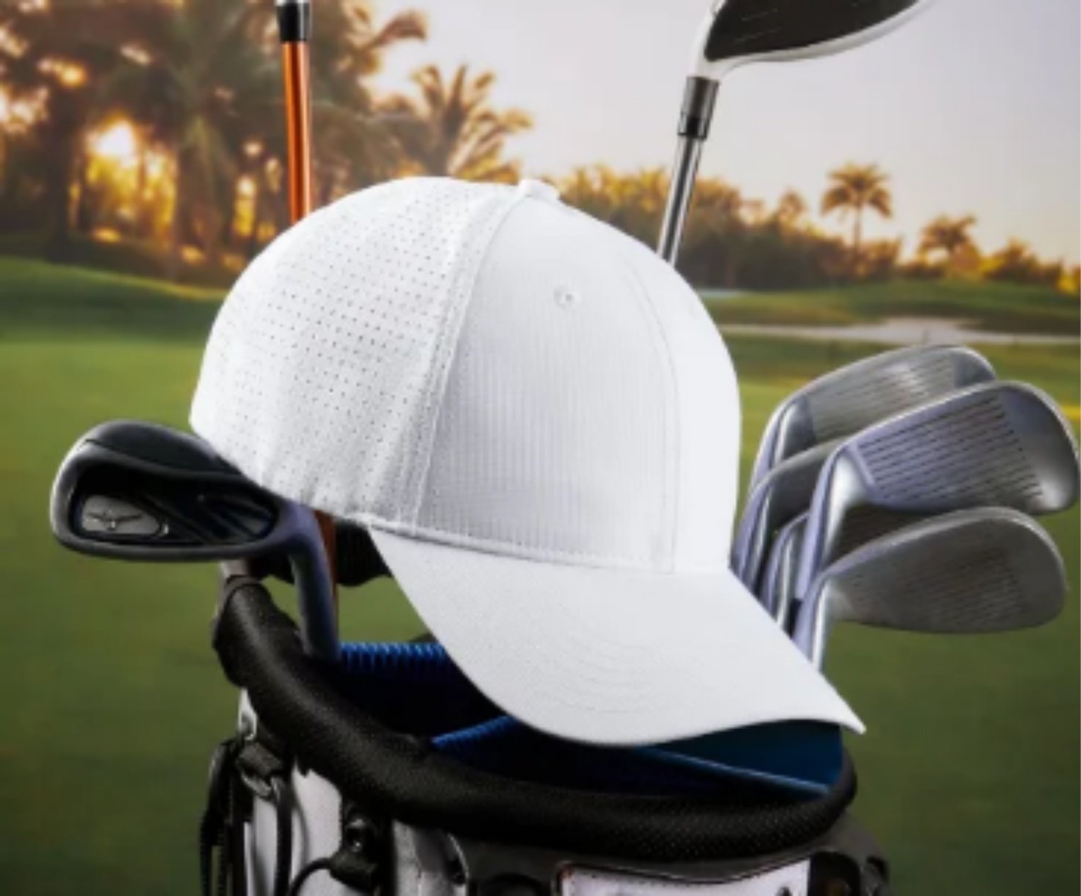White baseball cap on a golf bag filled with clubs, set against a golf course background with palm trees.