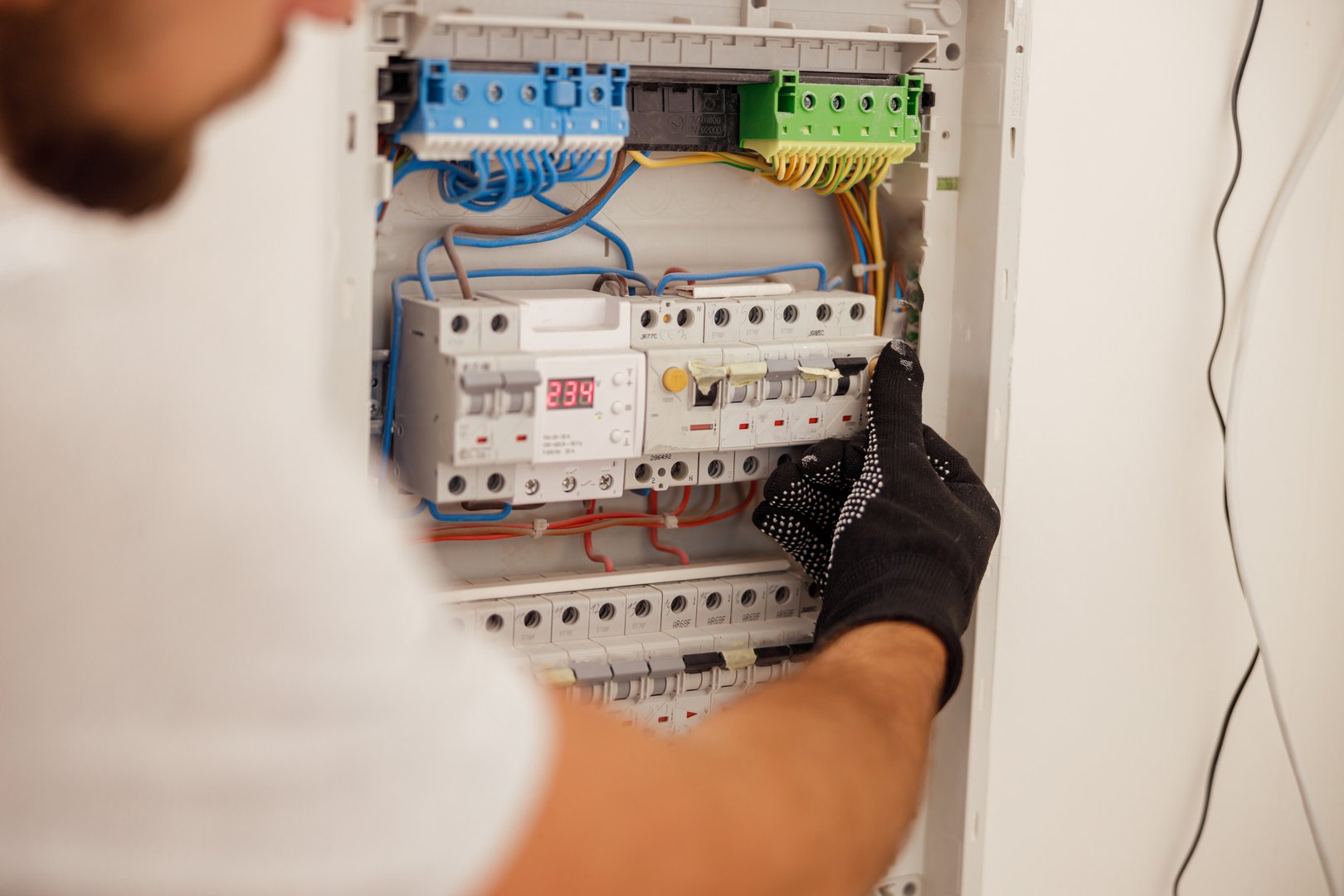 Hand of electrical technician working with fuses at the circuit breaker control cabinet on the wall. Manual work, maintenance, repair service concept