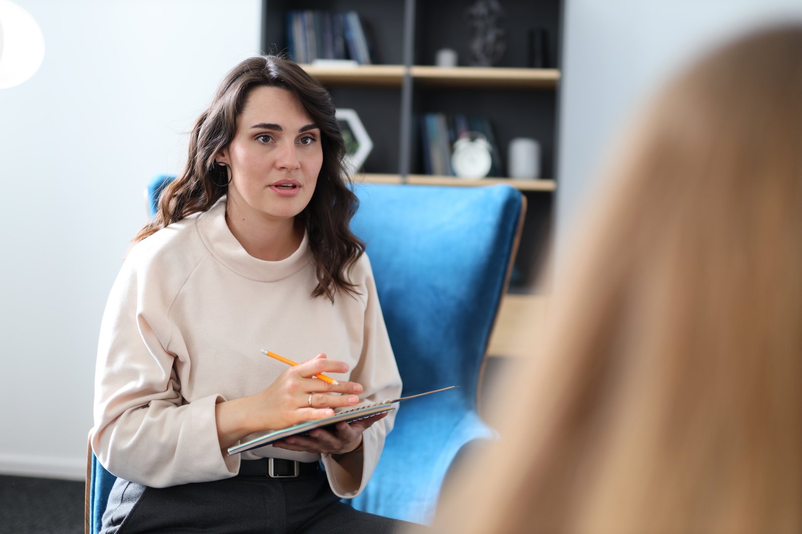 Caucasian female therapist listening and taking notes during therapy session.