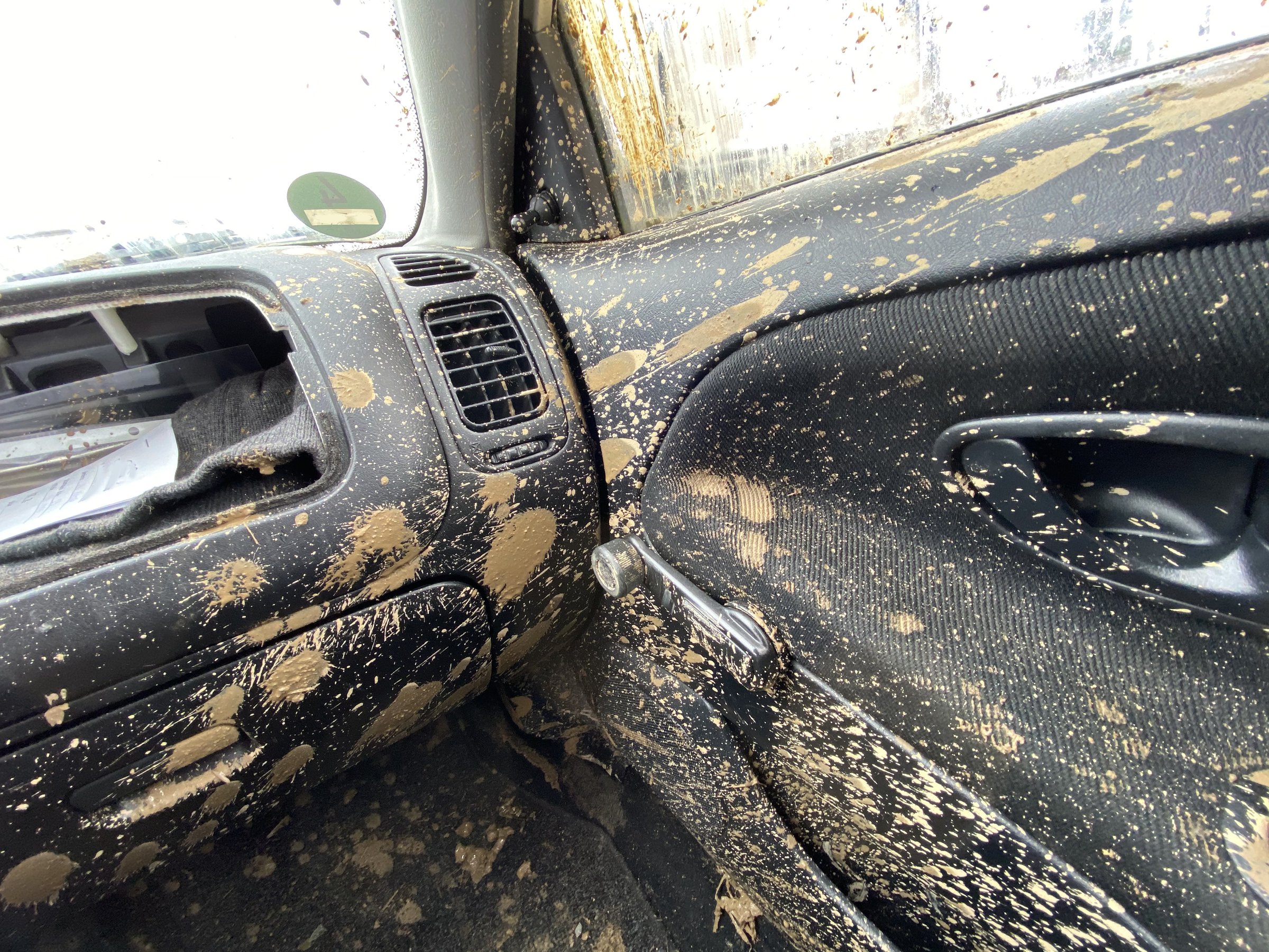 The detail of the car completely dirty by mud after the drag race on a field during winter. It needs complete cleaning of the exterior and interior.