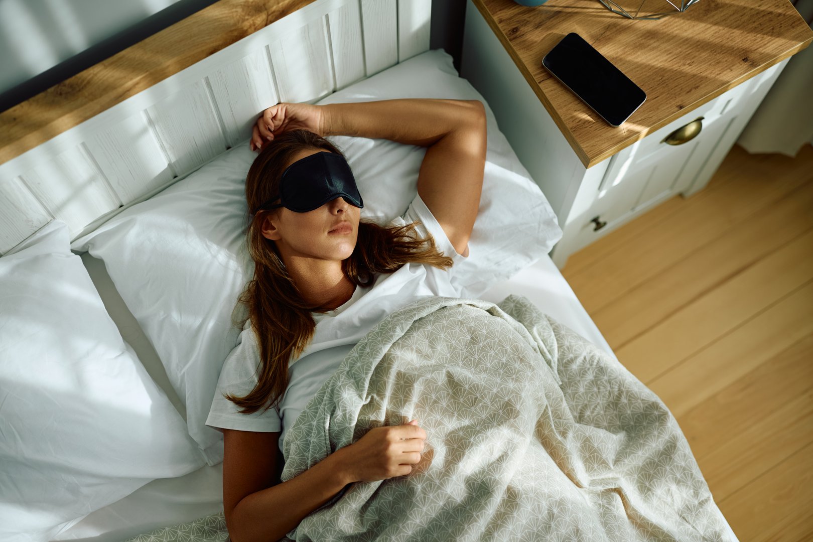 High angle view of woman wearing sleeping eye mask in bed