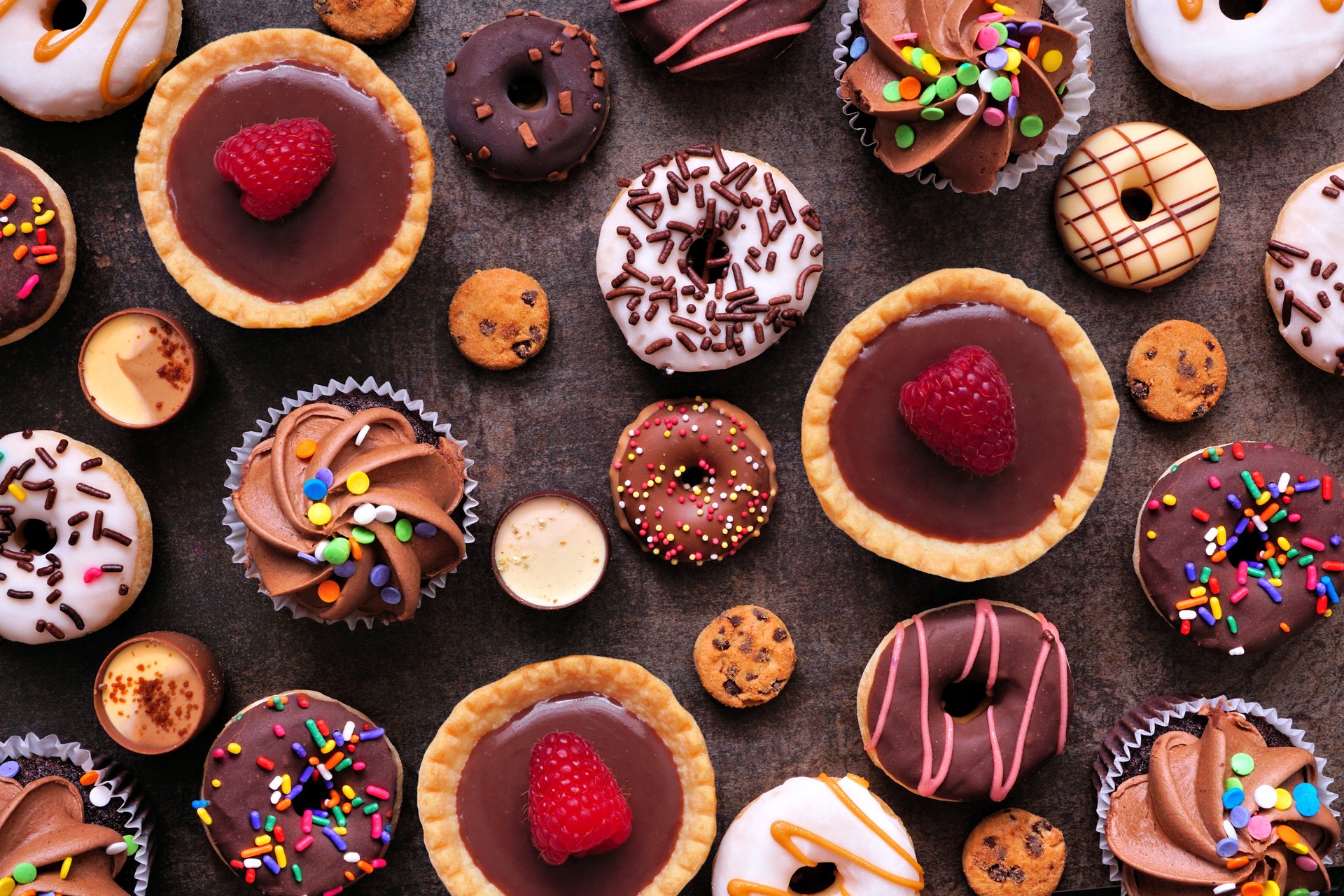 Dessert background with a selection of sweets. Top view on a dark stone background.