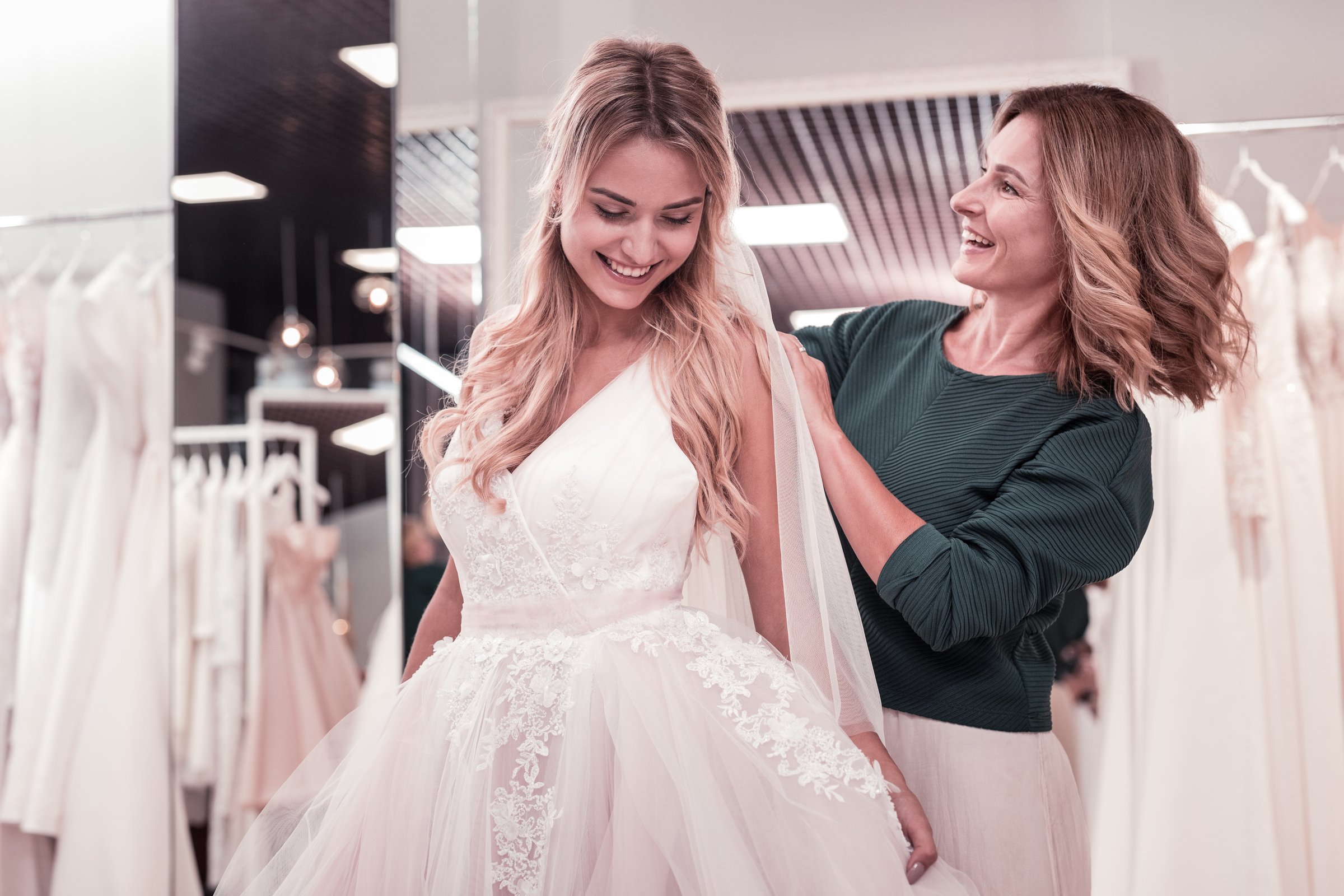 Beautiful bride. Cheerful young woman standing in front of her mother while wearing a wedding dress