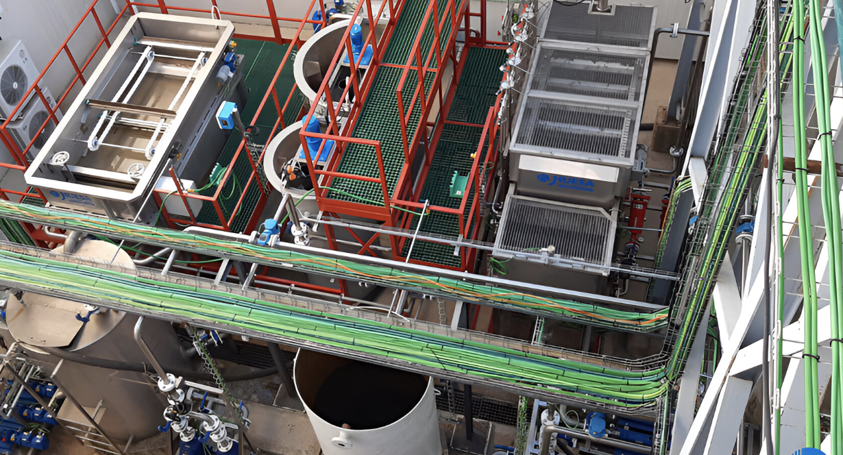 Aerial view of an industrial facility with tanks, pipes, and machinery, featuring a network of colorful overhead cables.