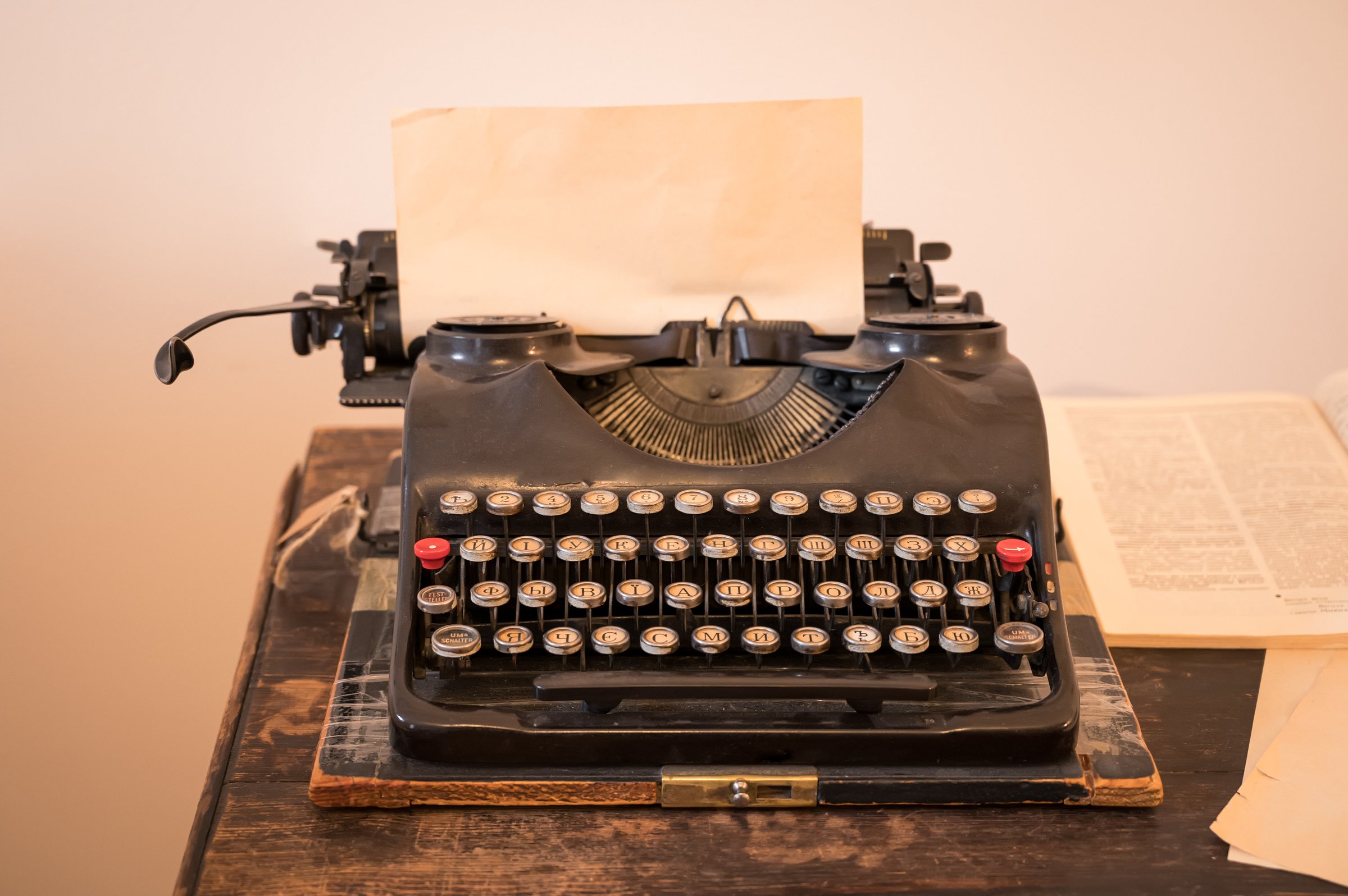 Vintage typewriter on wooden desk with blank paper, warm indoor lighting and retro writing atmosphere