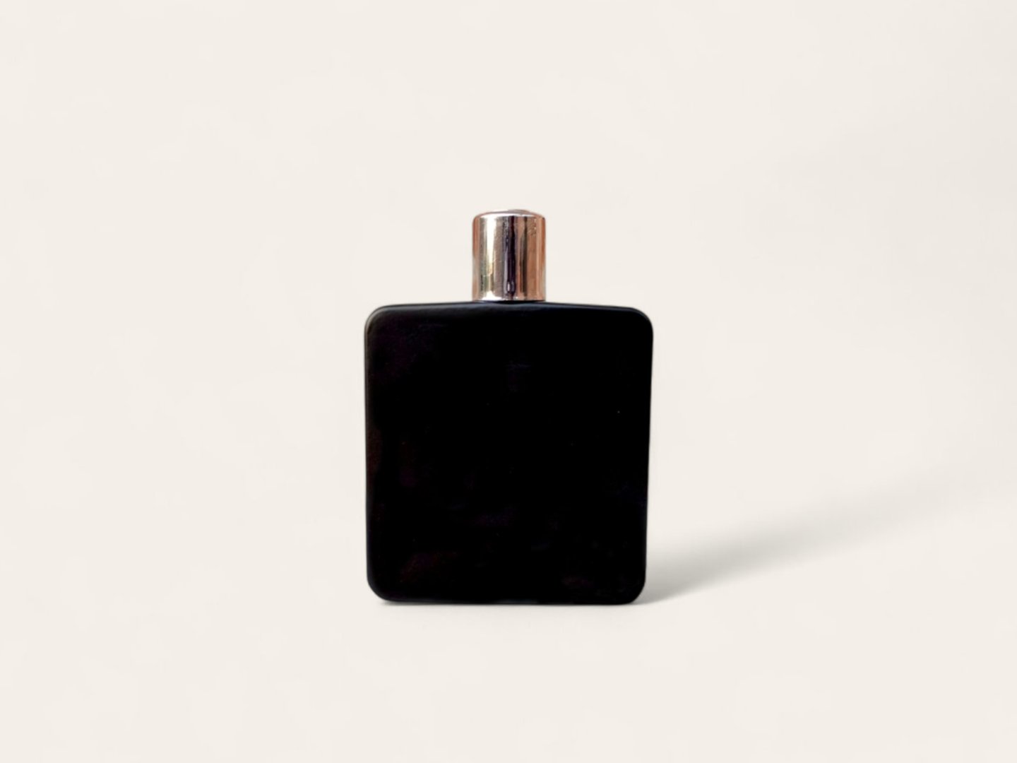 A modern and elegant black bottle, likely for perfume or cologne, is presented against a plain, off-white background.