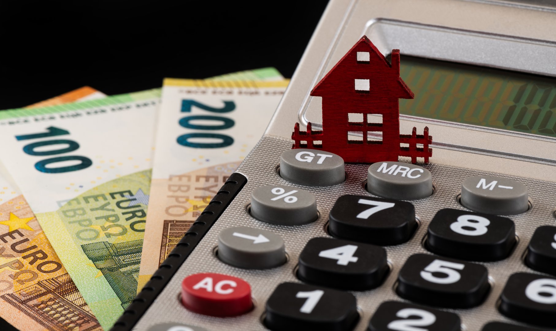 Mortgage savings concept showing house model, calculator and money representing prepayment strategies to save thousands in interest