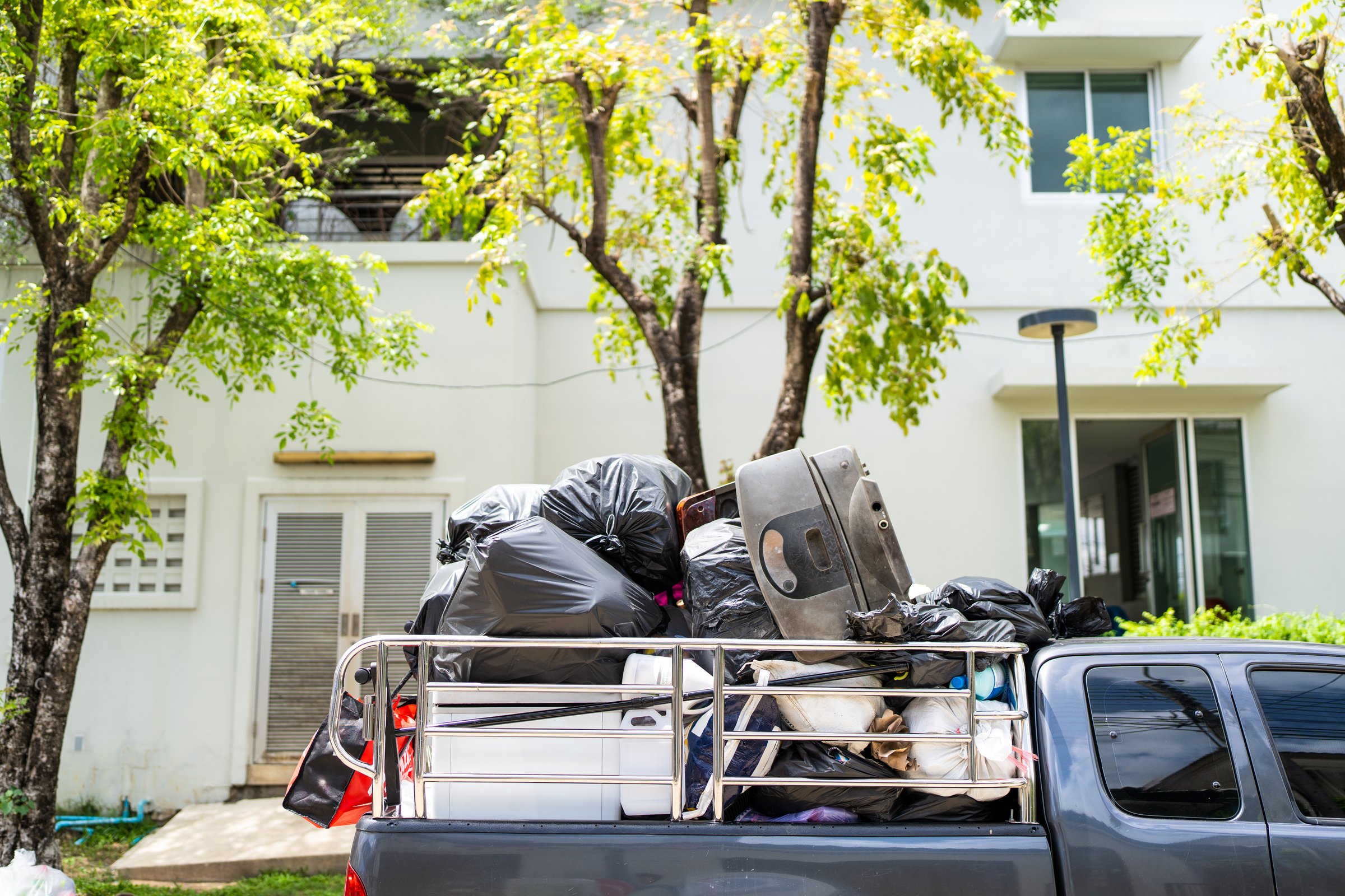 Pickup truck loaded with used goods and other scrap. Ready for recycling or disposal in sunny outdoor setting.